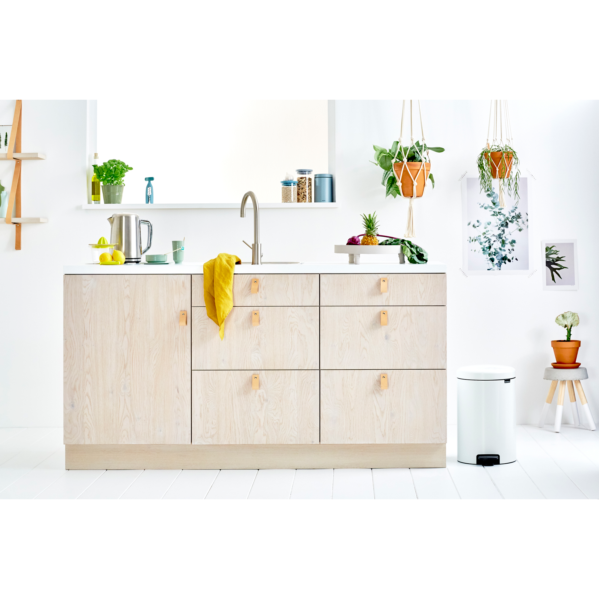 Een lichte keuken met houten kasten, fruit en planten.