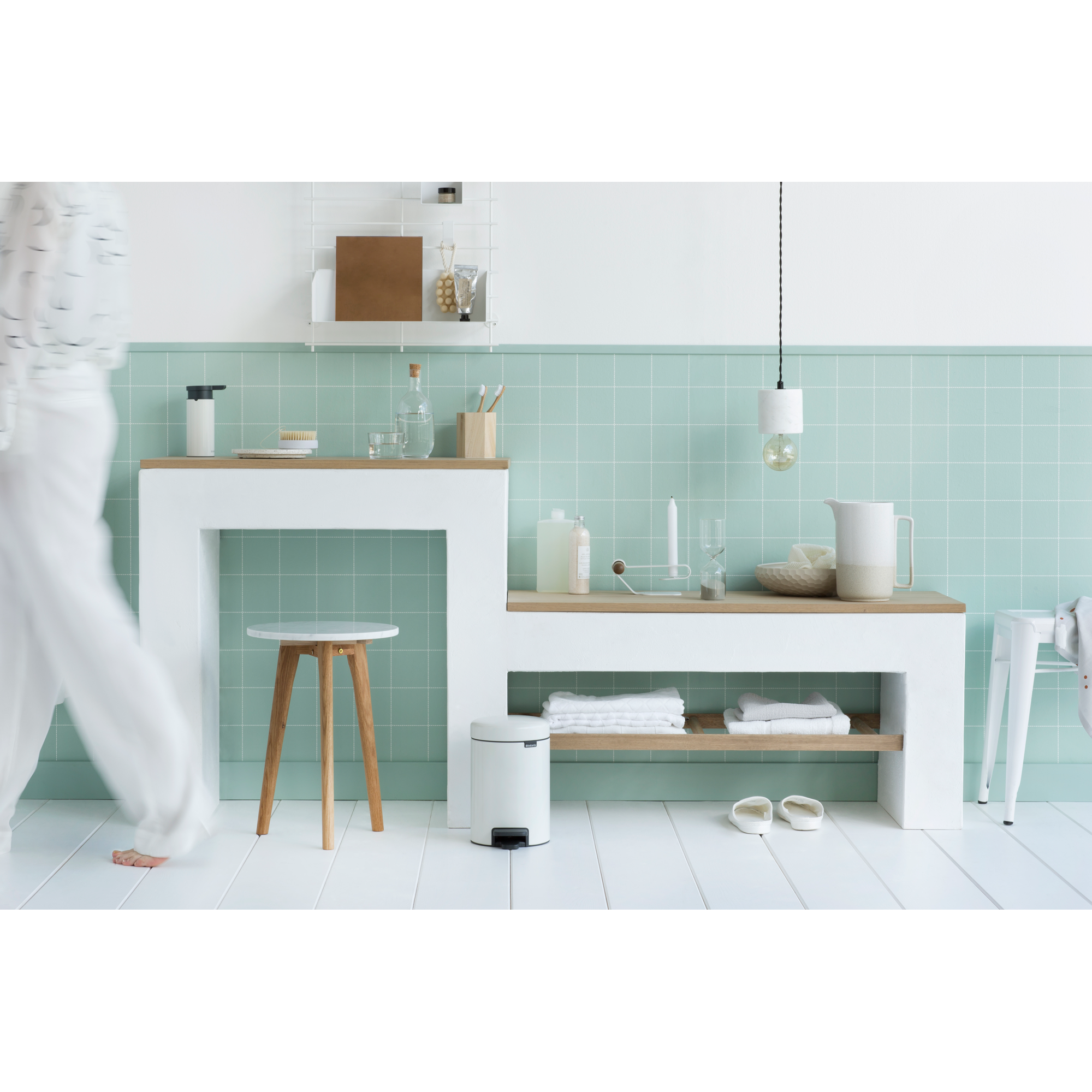 Een badkamer met lichtgroene tegels, wit meubilair en houten accenten.