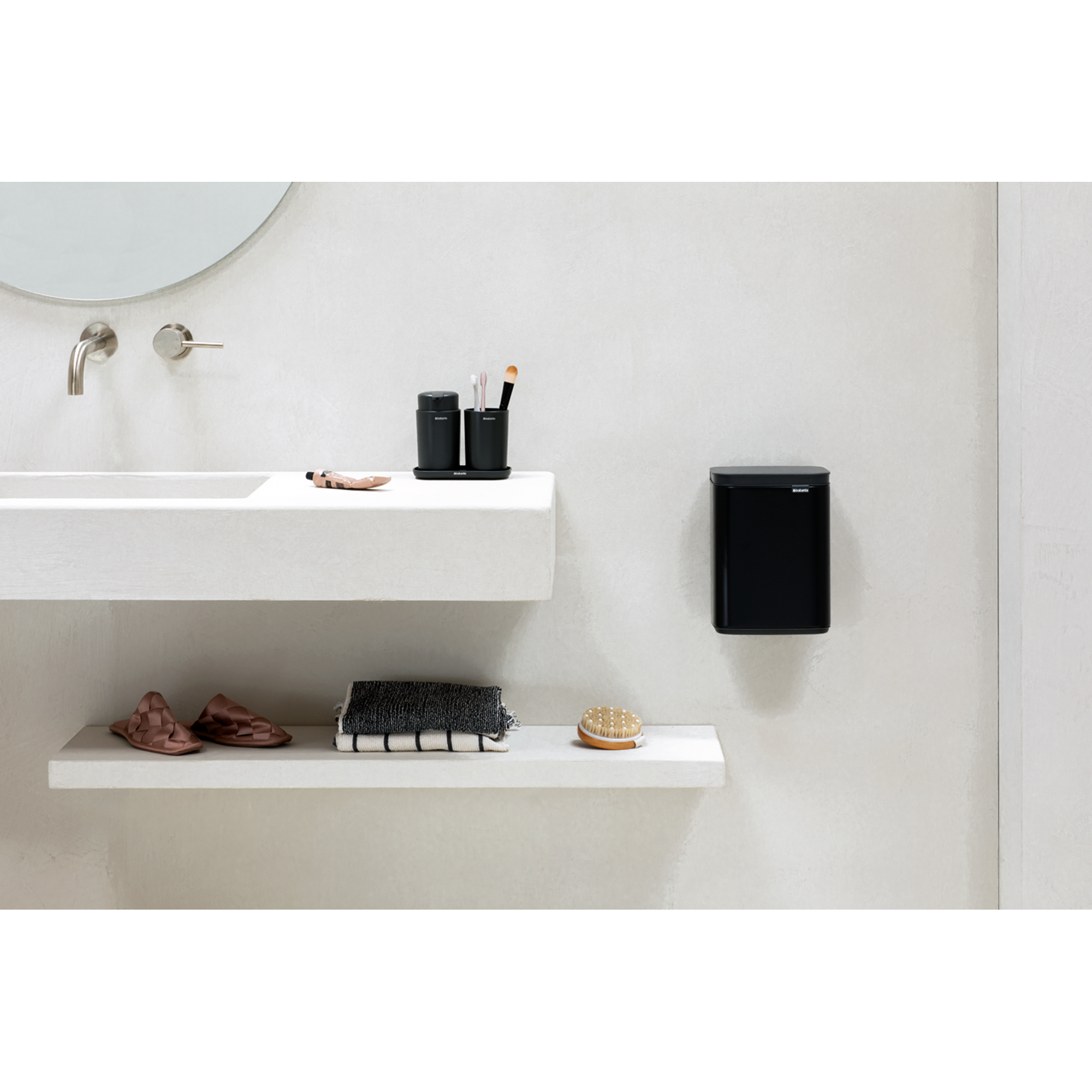 Moderne badkamer: wastafel, planken met slippers, handdoeken, borstel en zwarte prullenbak.