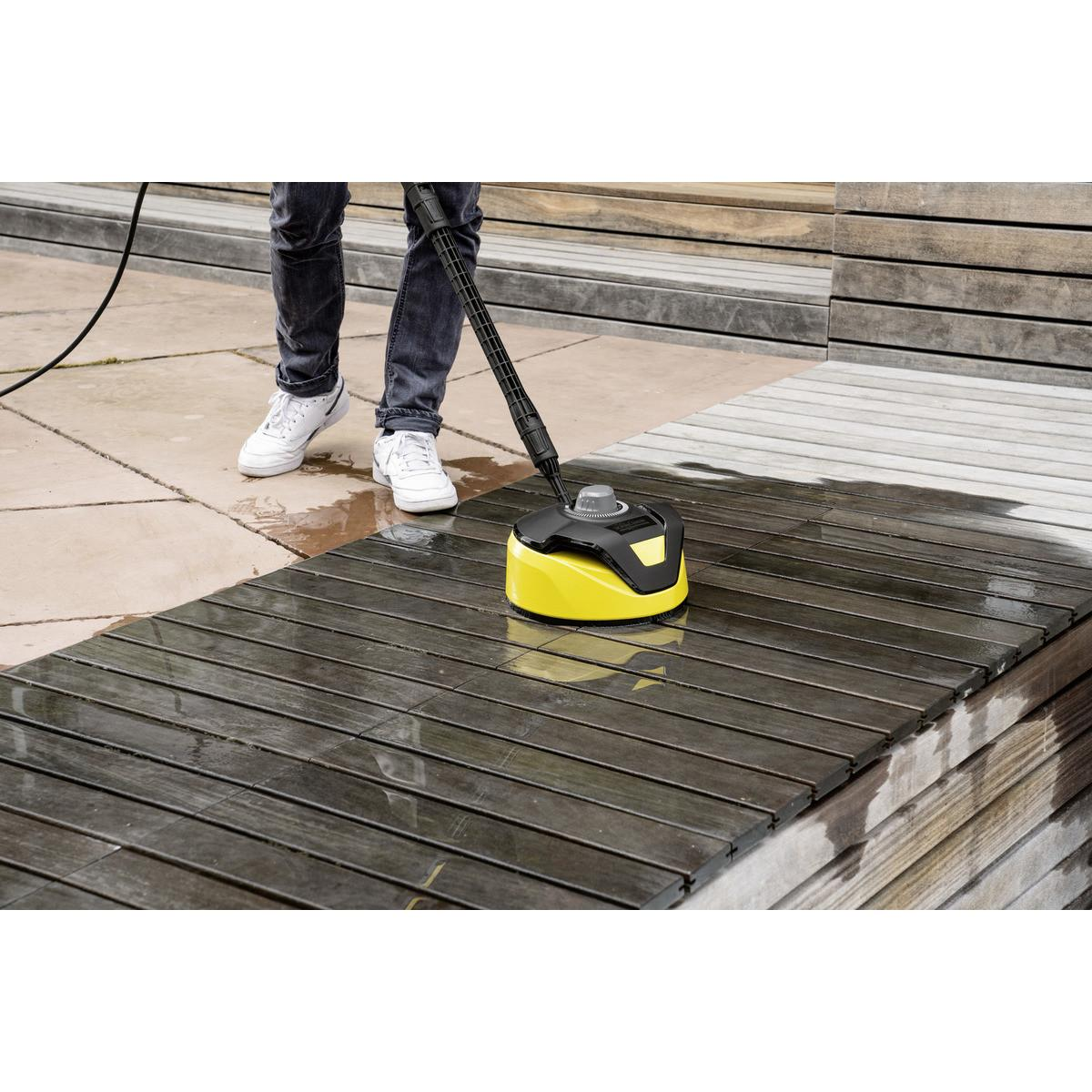 Una persona pulisce un ponte di legno con un accessorio idropulitrice giallo.
