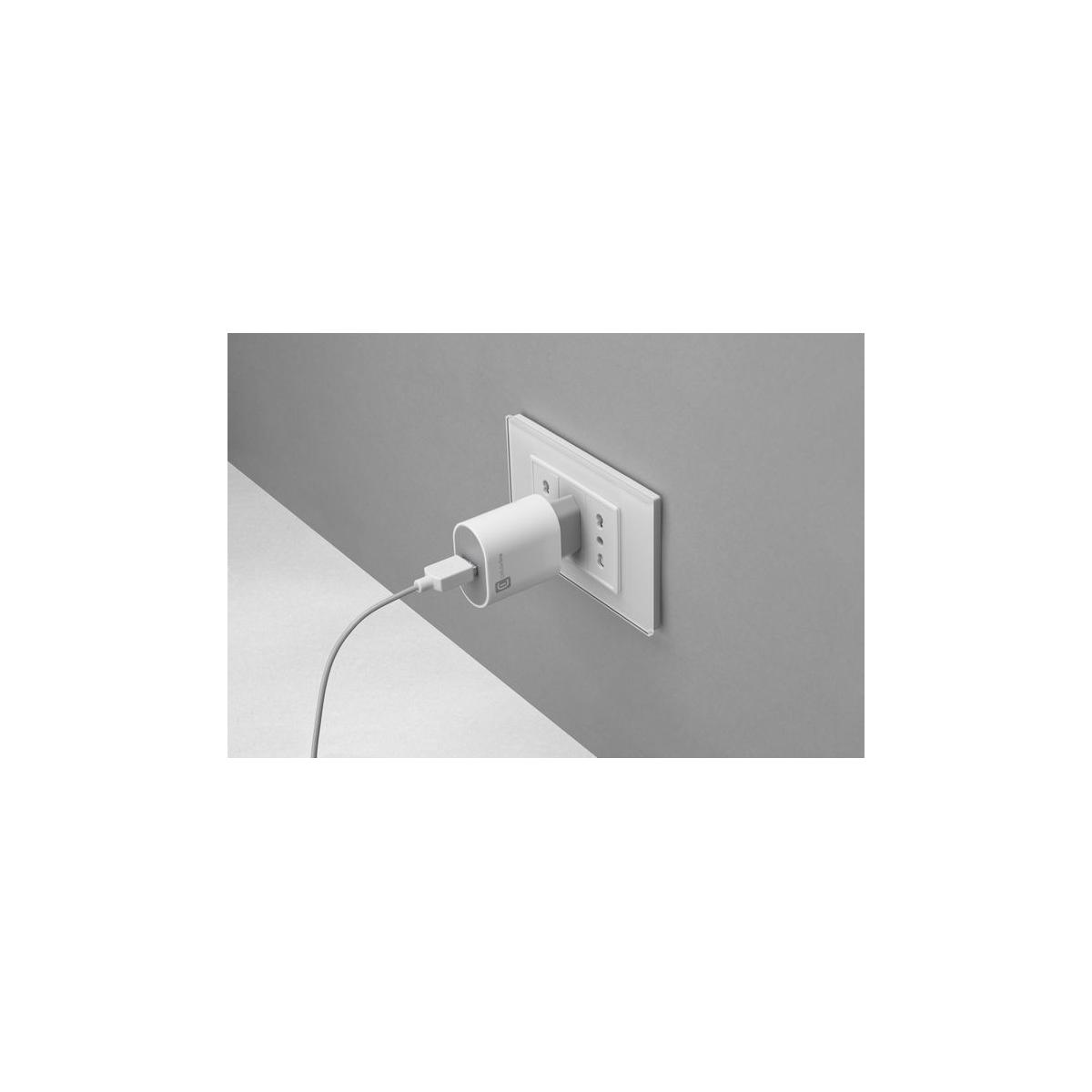 Un adaptador de corriente blanco está enchufado a un enchufe de pared blanco.