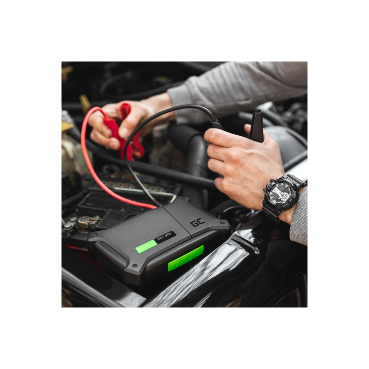 Una persona usa un avviatore di emergenza nero con indicatori verdi per avviare una batteria per auto.
