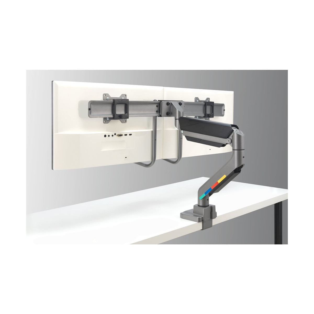 Gray dual monitor arm mounted on a white desk.