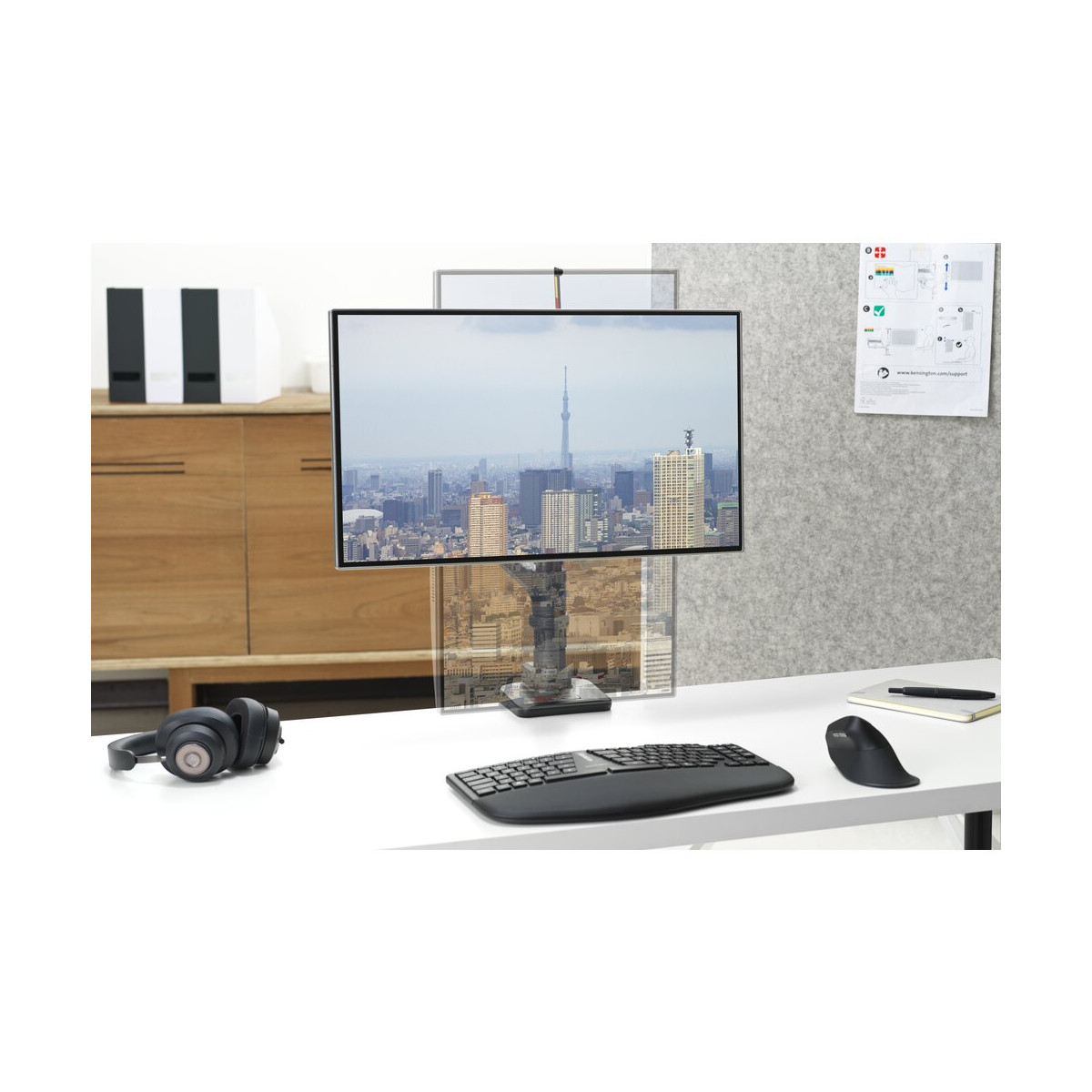 Un bureau avec un moniteur affichant une vue de ville, un casque, un clavier et une souris.