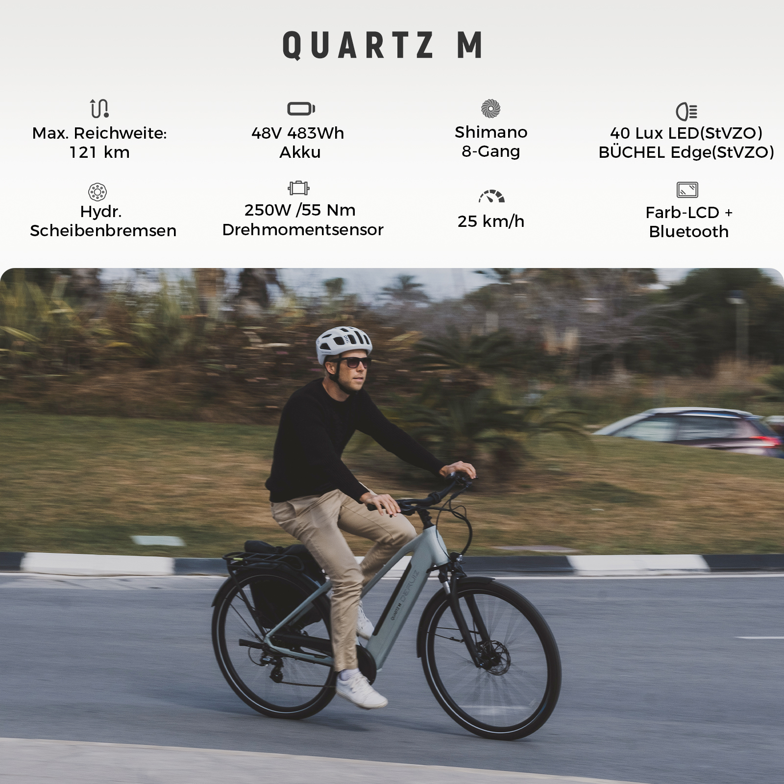 Ein Mann fährt ein graues E-Bike mit Helm und Sonnenbrille auf einer Straße.