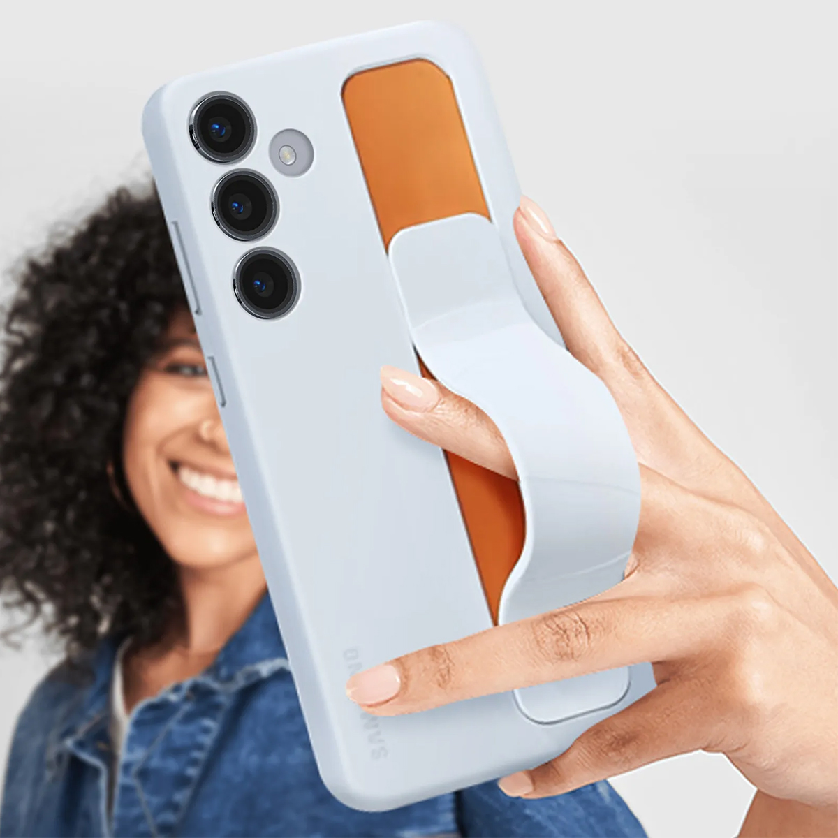 Una mano sostiene un teléfono azul claro con inserción naranja y correa blanca.