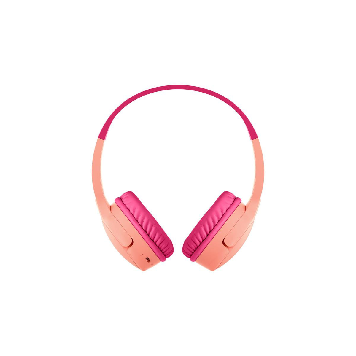 Une paire de écouteurs corail avec coussinets et arceau roses. Isolé.