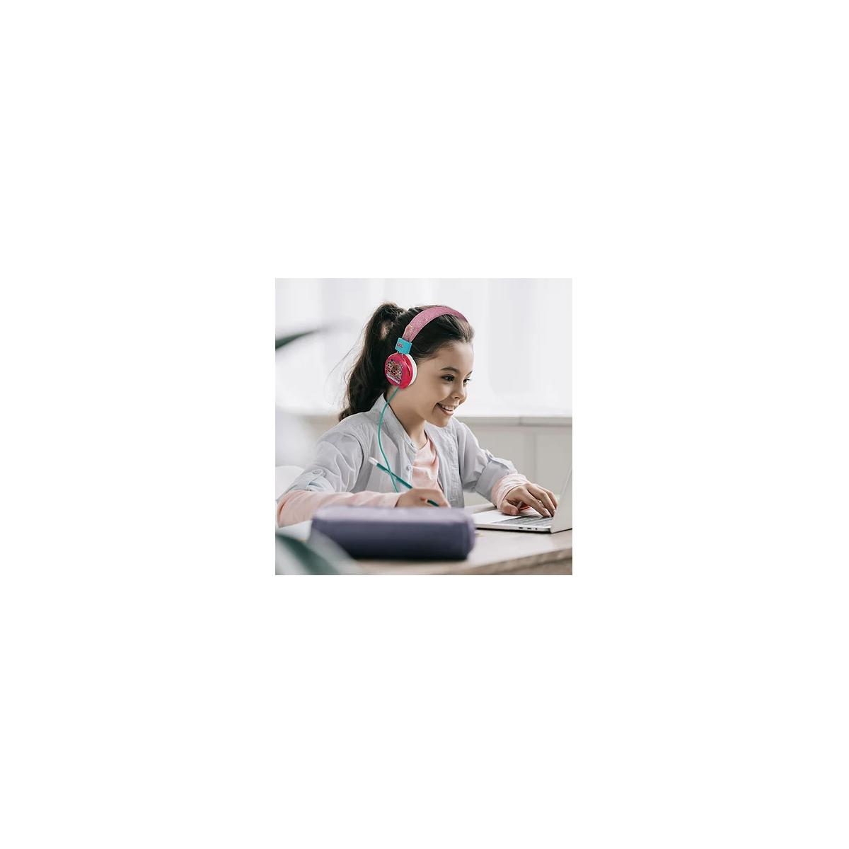 Una niña con auriculares sonríe mirando una laptop.