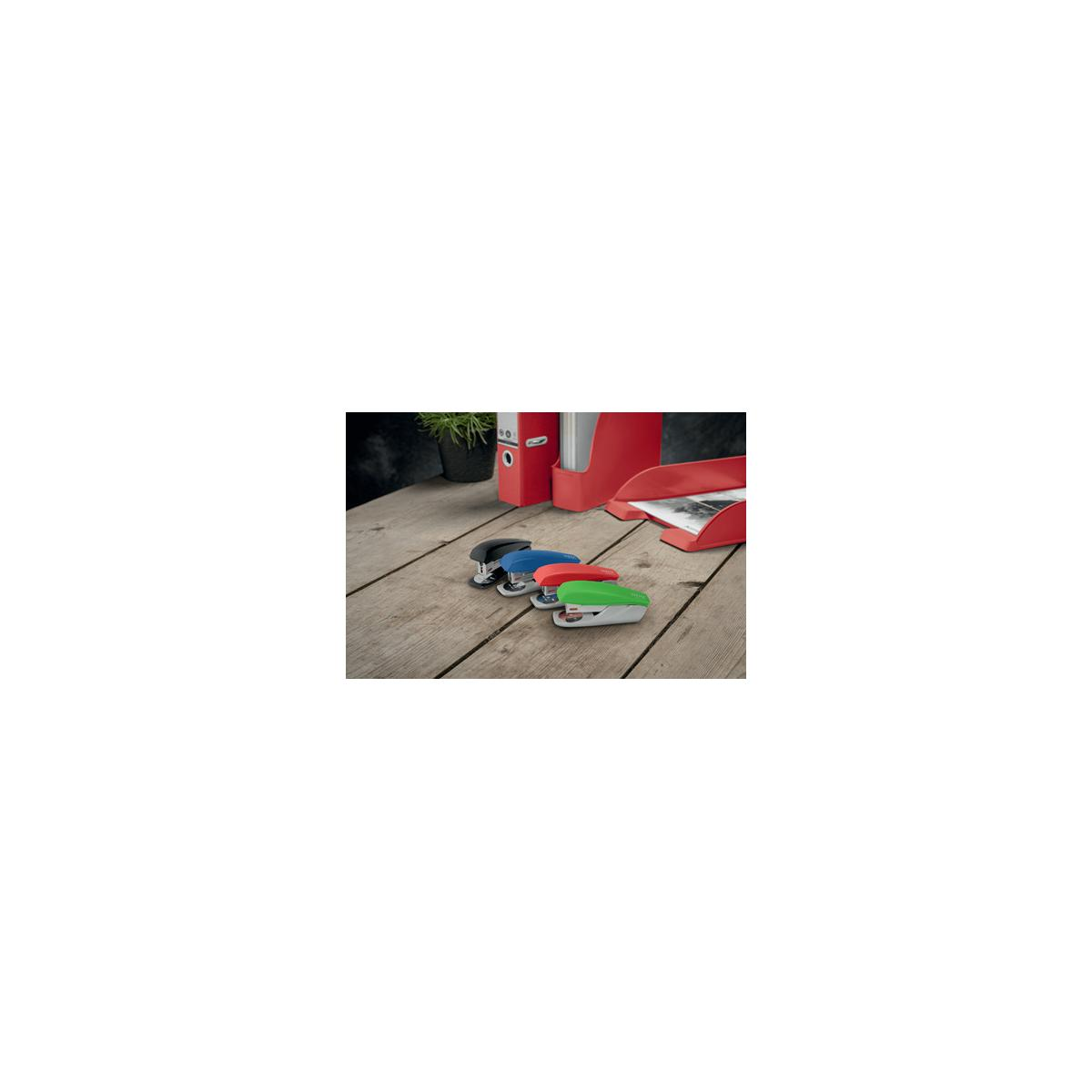 Quattro graffettatrici colorate su un tavolo di legno accanto a una cartellina rossa.