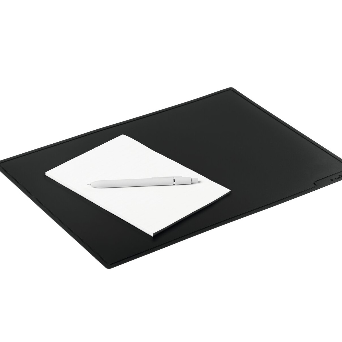 Ein weißes Notizbuch und ein grauer Stift liegen auf einer schwarzen Matte. Weißer Hintergrund.