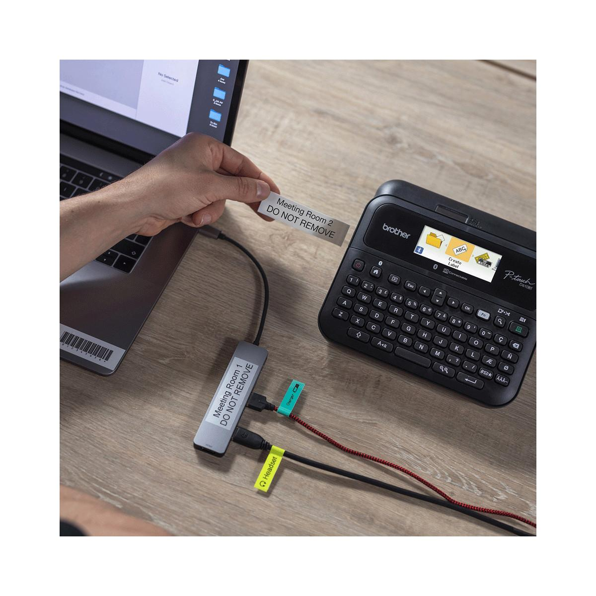Eine Hand beschriftet einen USB-Hub mit 'Meeting Room 2 DO NOT REMOVE'.