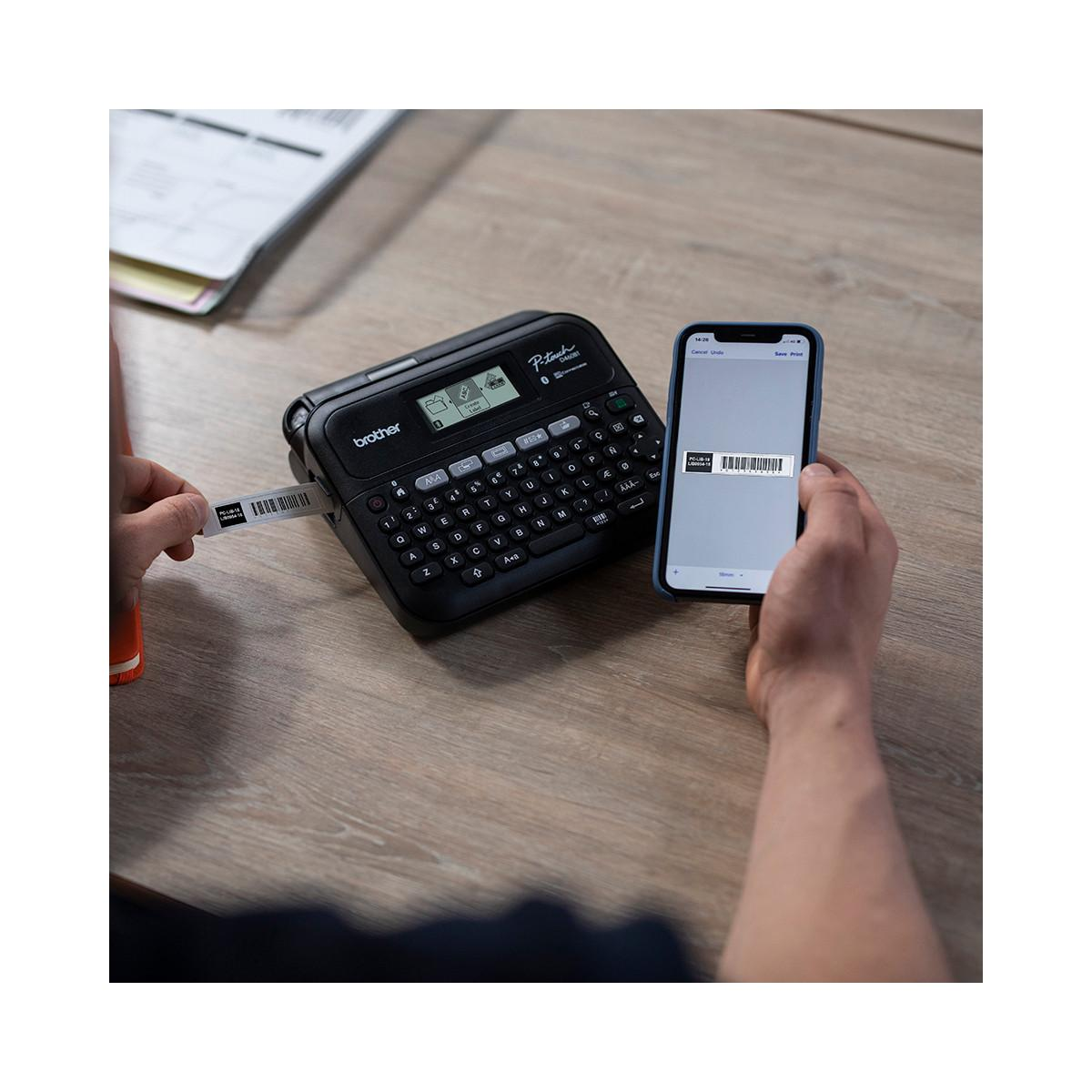 Ein Mann benutzt einen Etikettendrucker und ein Smartphone auf einem Holztisch.