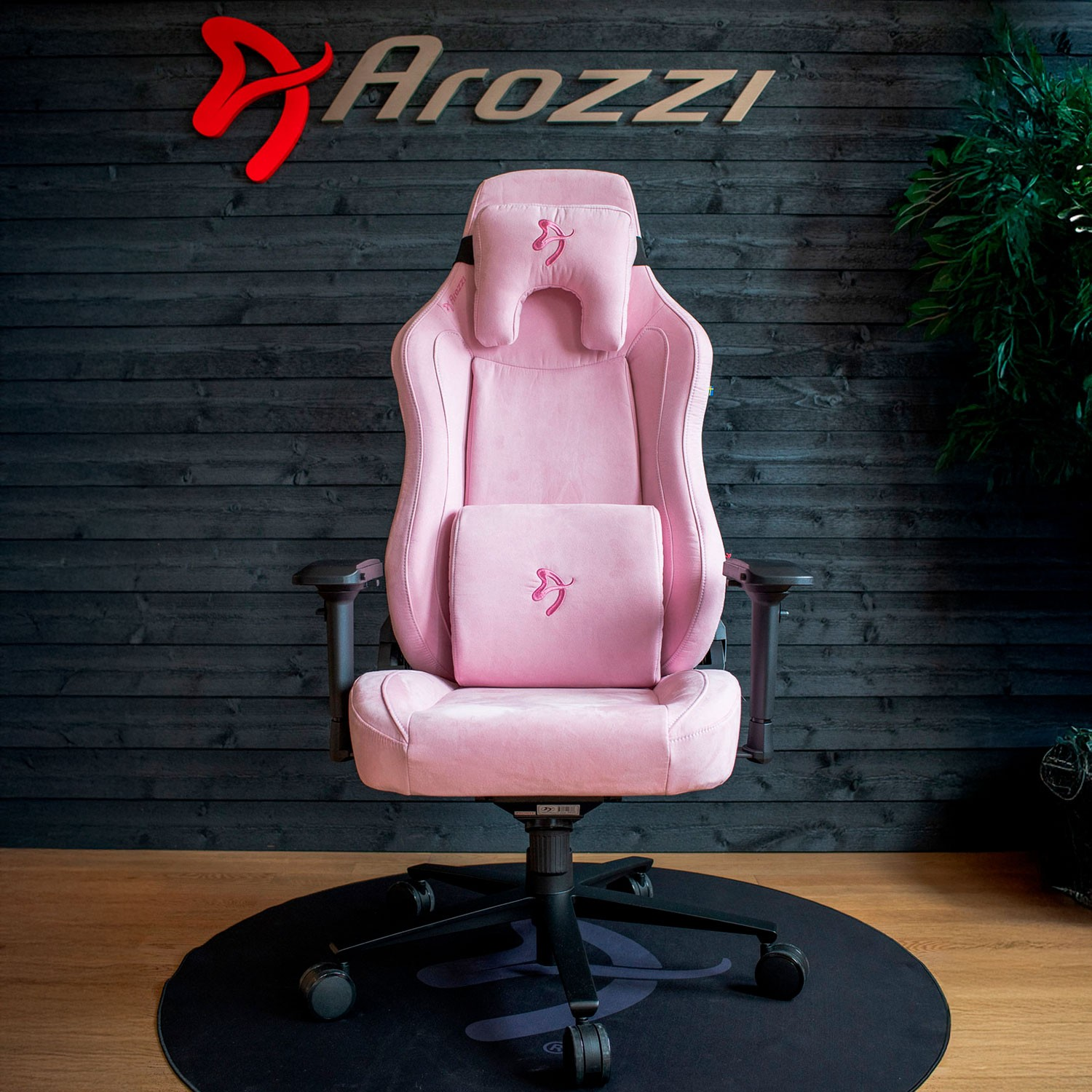 Ein rosafarbener Gaming-Stuhl mit Kissen steht vor einer dunklen Holzvertäfelung.