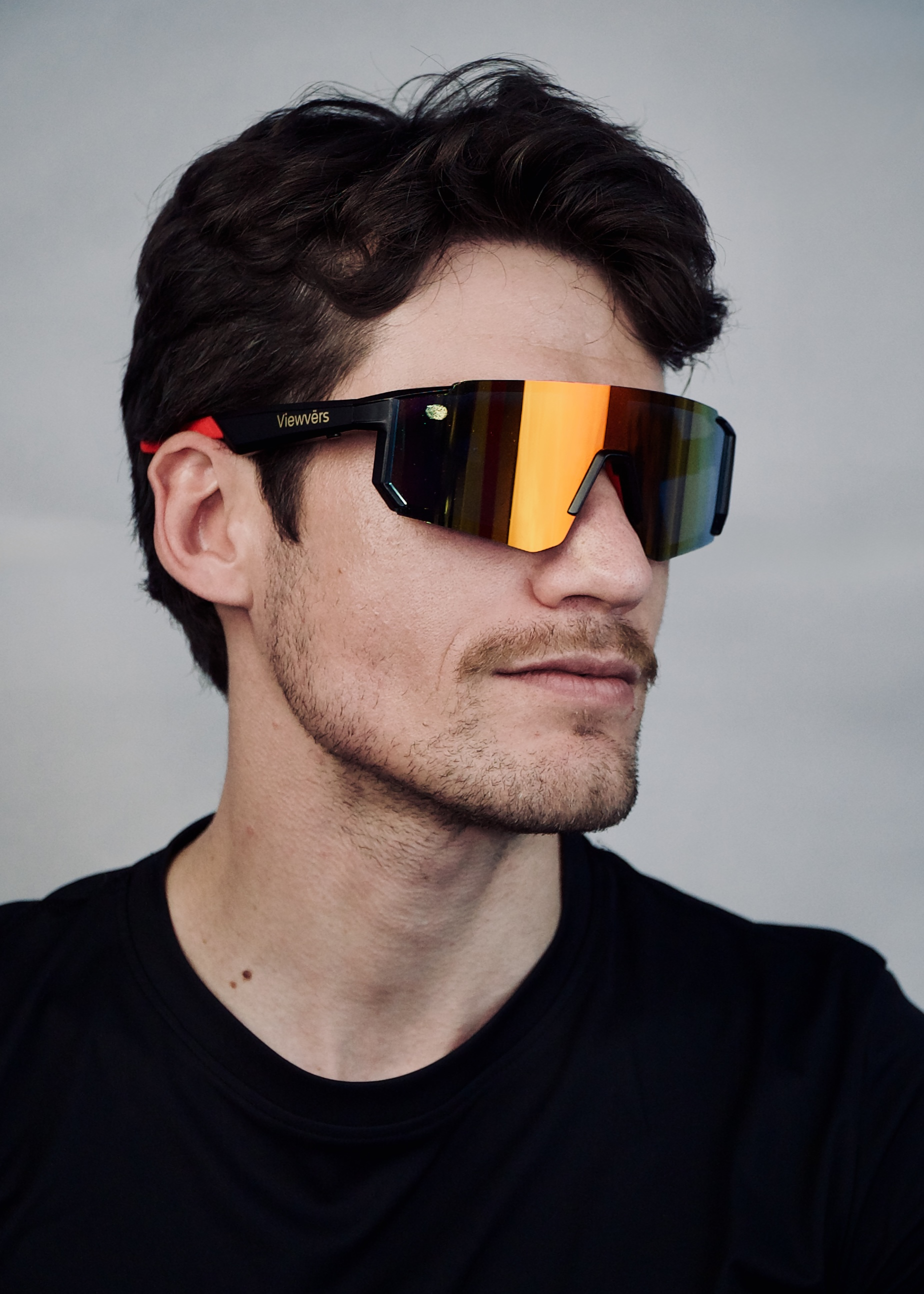 Hombre de cabello oscuro usa gafas de sol negras con lentes naranjas.
