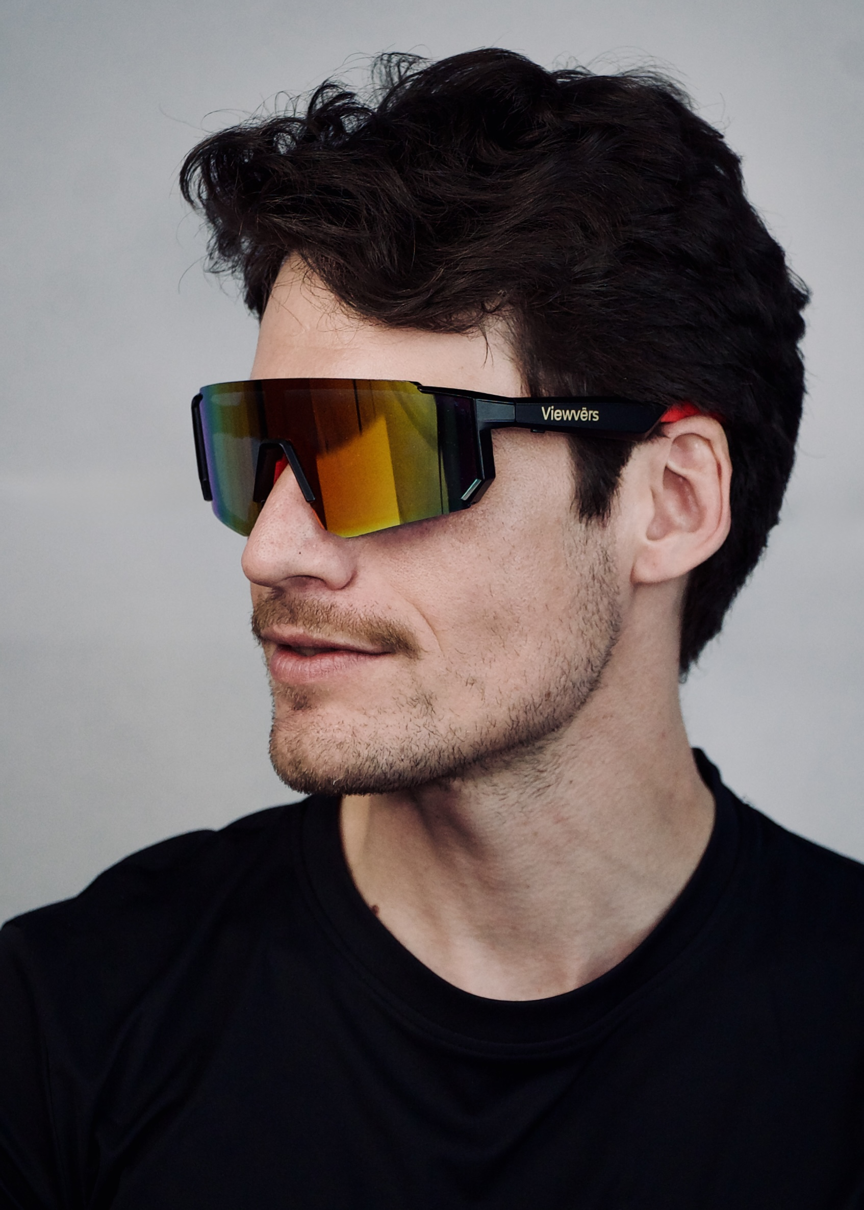 Hombre de cabello oscuro usa gafas de sol negras con visera espejada.