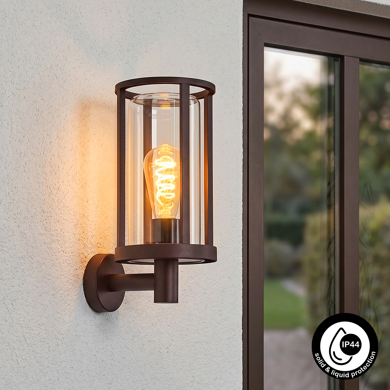 Eine braune Wandleuchte mit Glaszylinder und Glühbirne, neben einem Fenster.