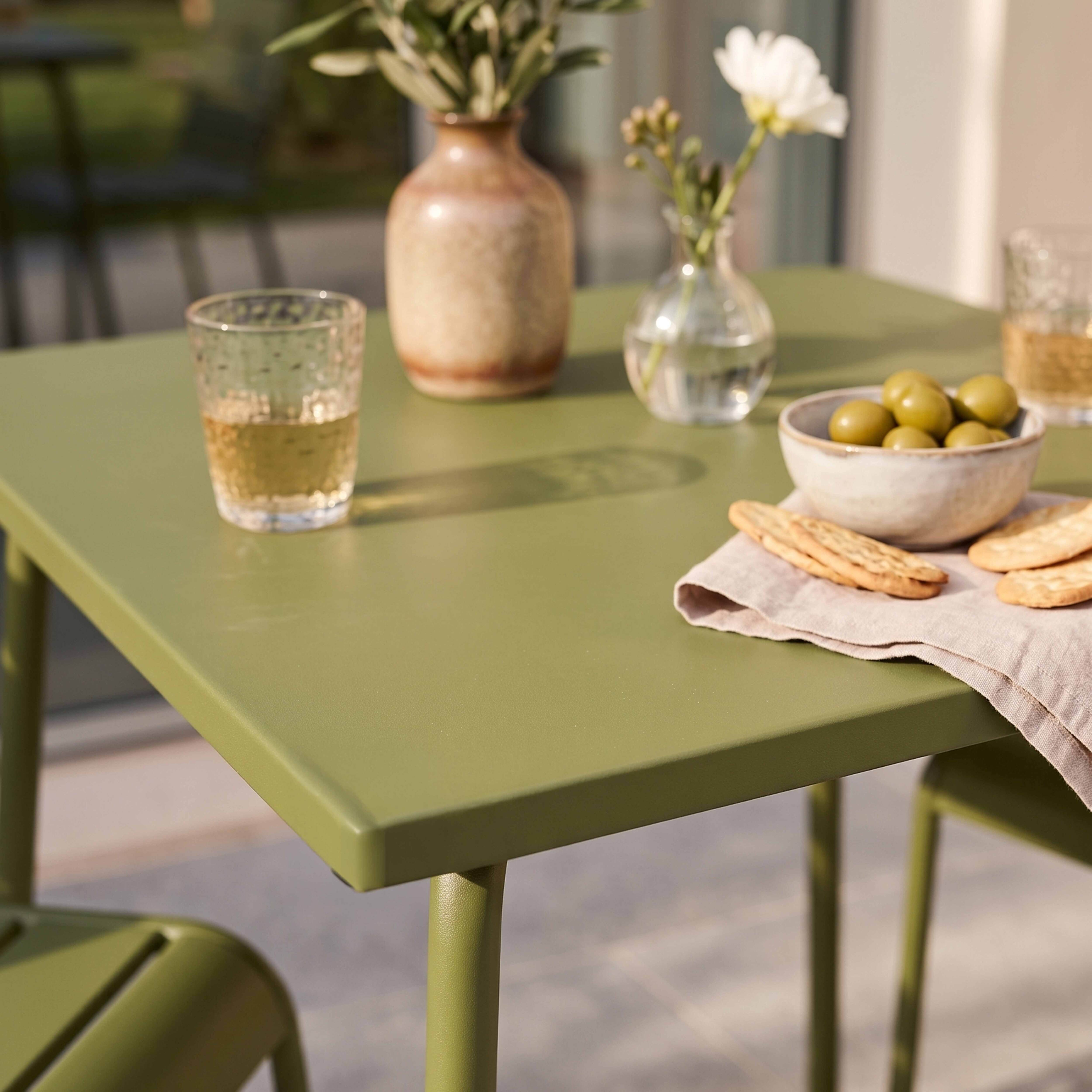 Grüner Tisch mit Oliven, Crackern und Gläsern mit Getränken.