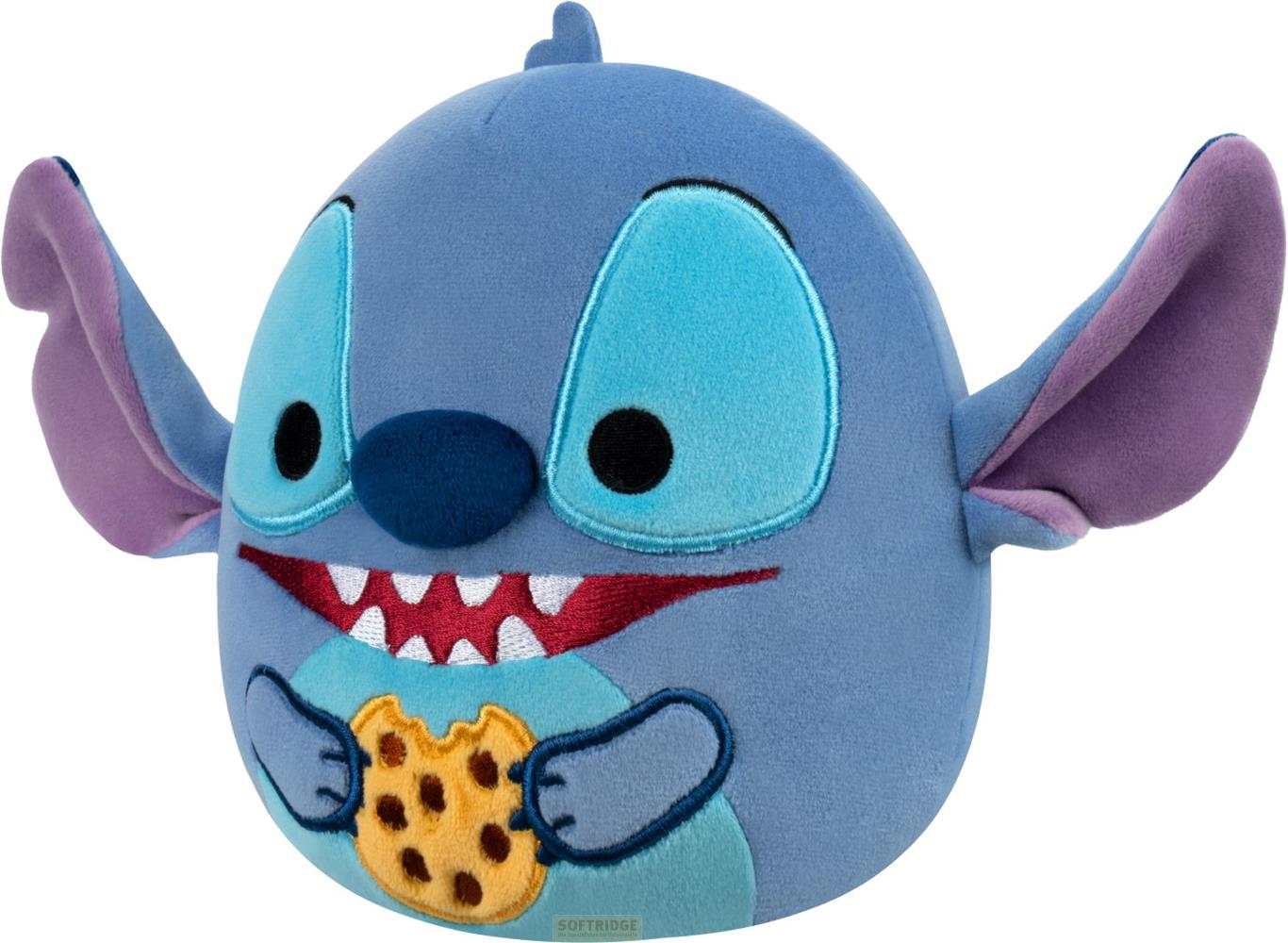 Ein blauer Stitch-Plüsch hält einen Keks, mit großen Ohren und einem breiten Grinsen.