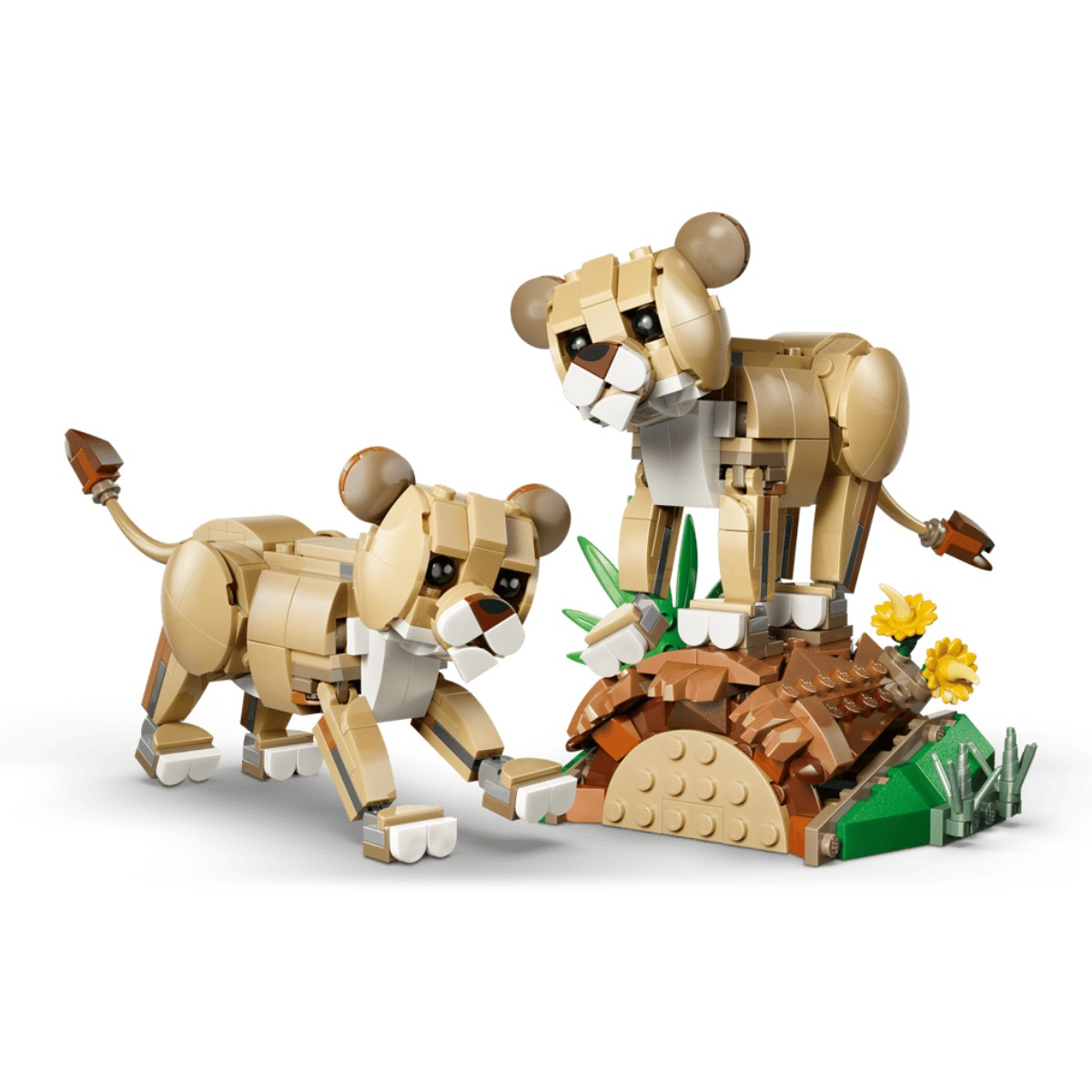 Dos cachorros de león de lego sobre una base rocosa con plantas verdes y flores amarillas.