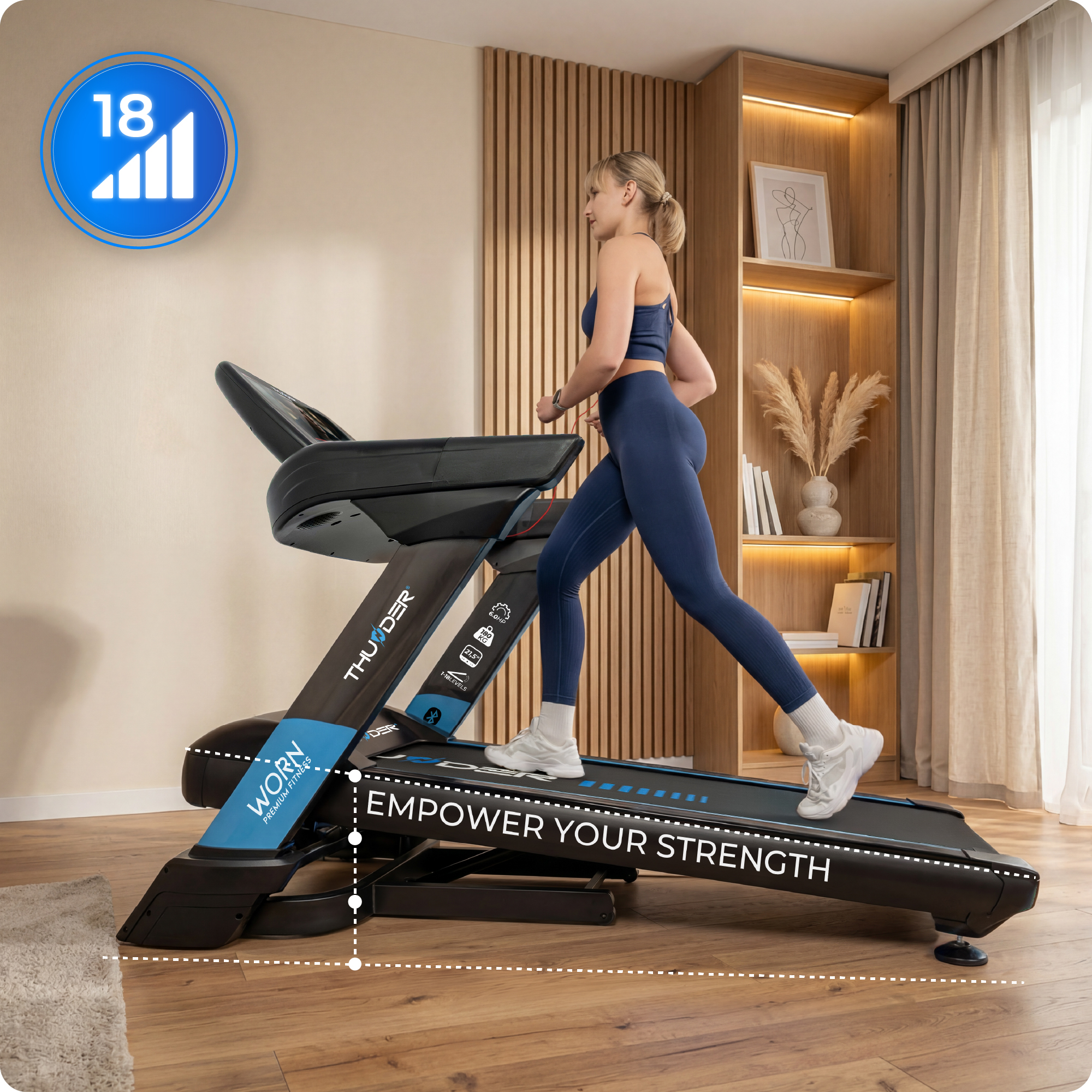 Eine Frau läuft auf einem Laufband in einem modernen Wohnzimmer. Das Laufband hat blaue Akzente und die Aufschrift „EMPOWER YOUR STRENGTH“.