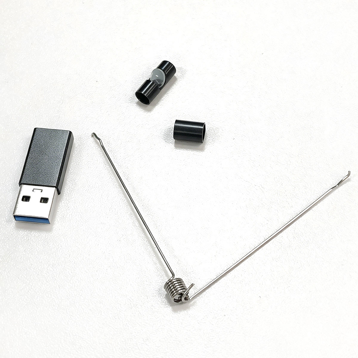 Ein USB-Stick und Metallfederkomponenten auf weißem Untergrund.