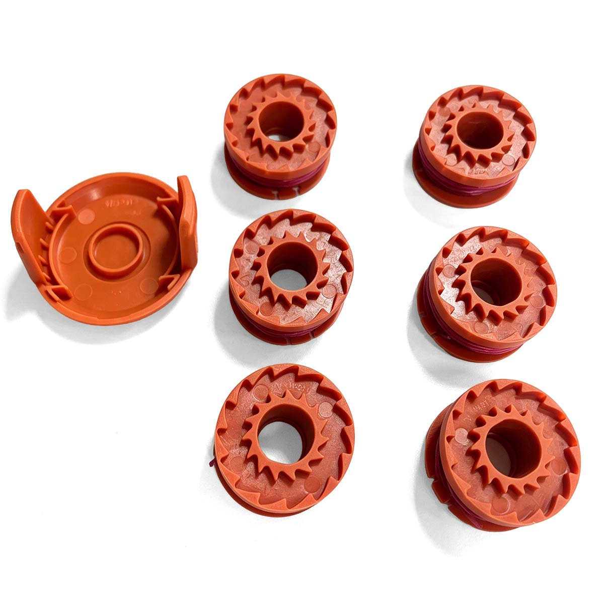 Een oranje spoelkop en vijf spoelen met lijn op een witte achtergrond.