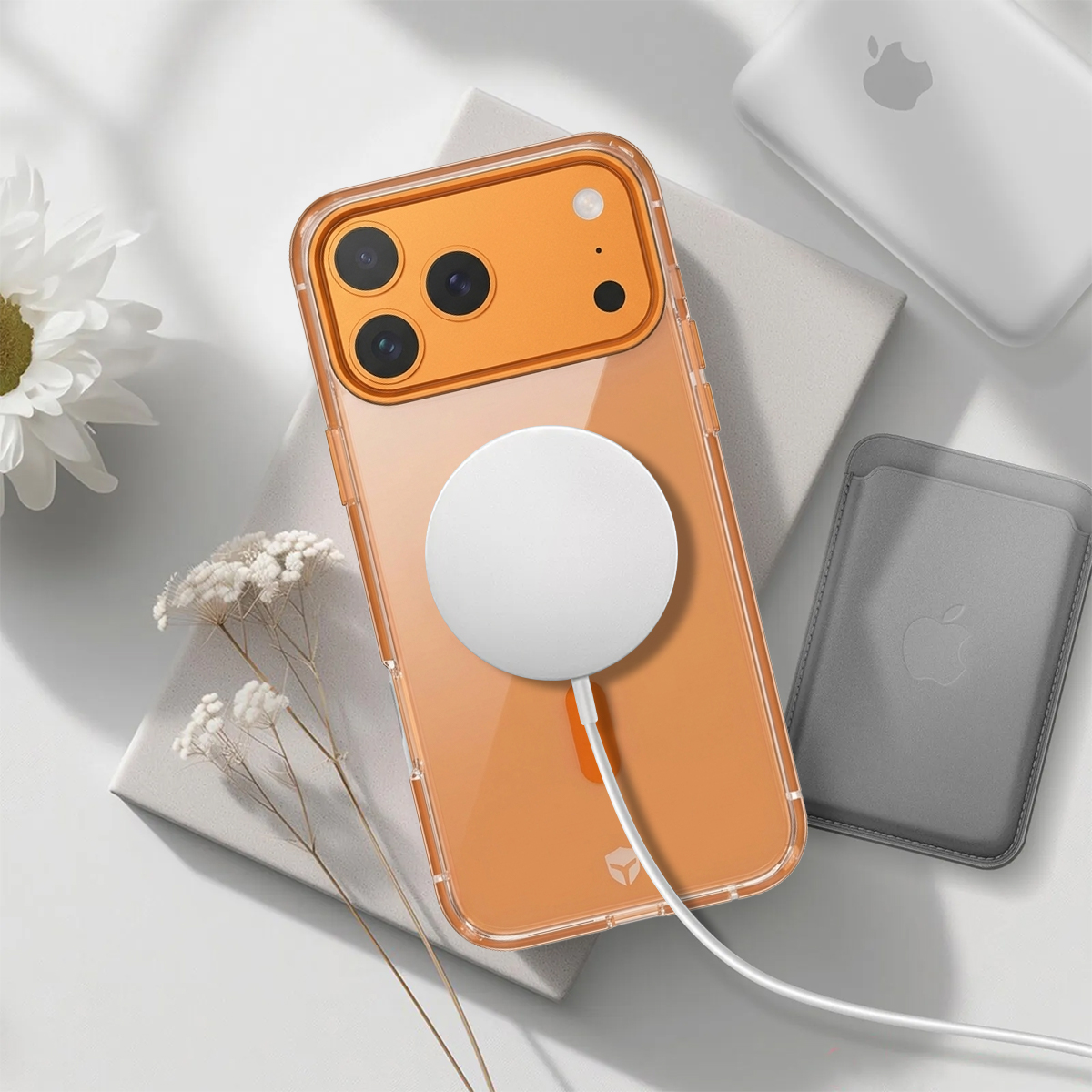 Ein oranges iPhone mit angeschlossenem weißem MagSafe-Ladegerät, neben einem grauen Kartenhalter.