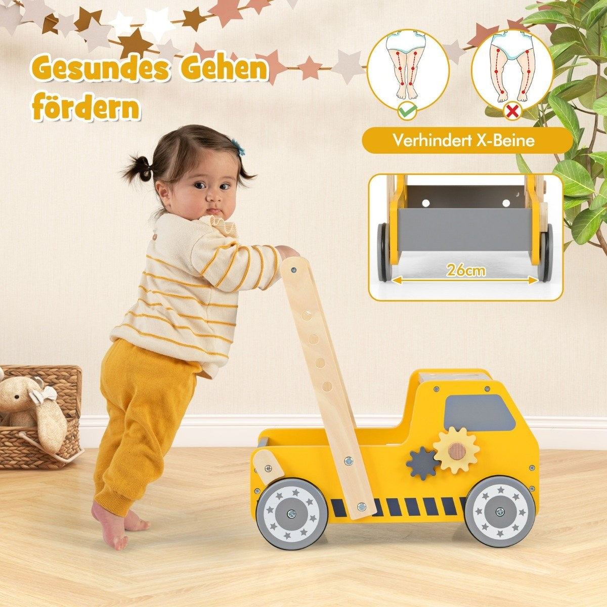 A baby leans on a yellow toy truck walker.