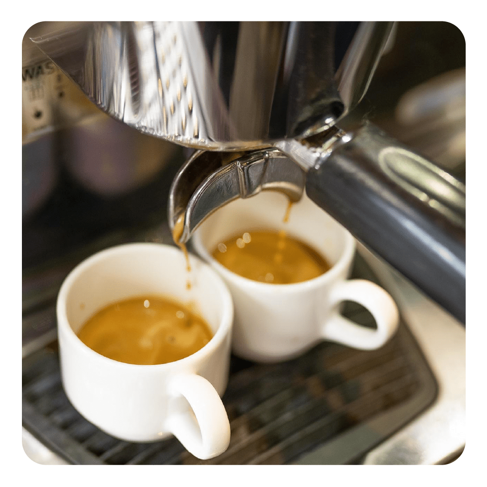 Espresso fließt aus einer Maschine in zwei weiße Tassen.