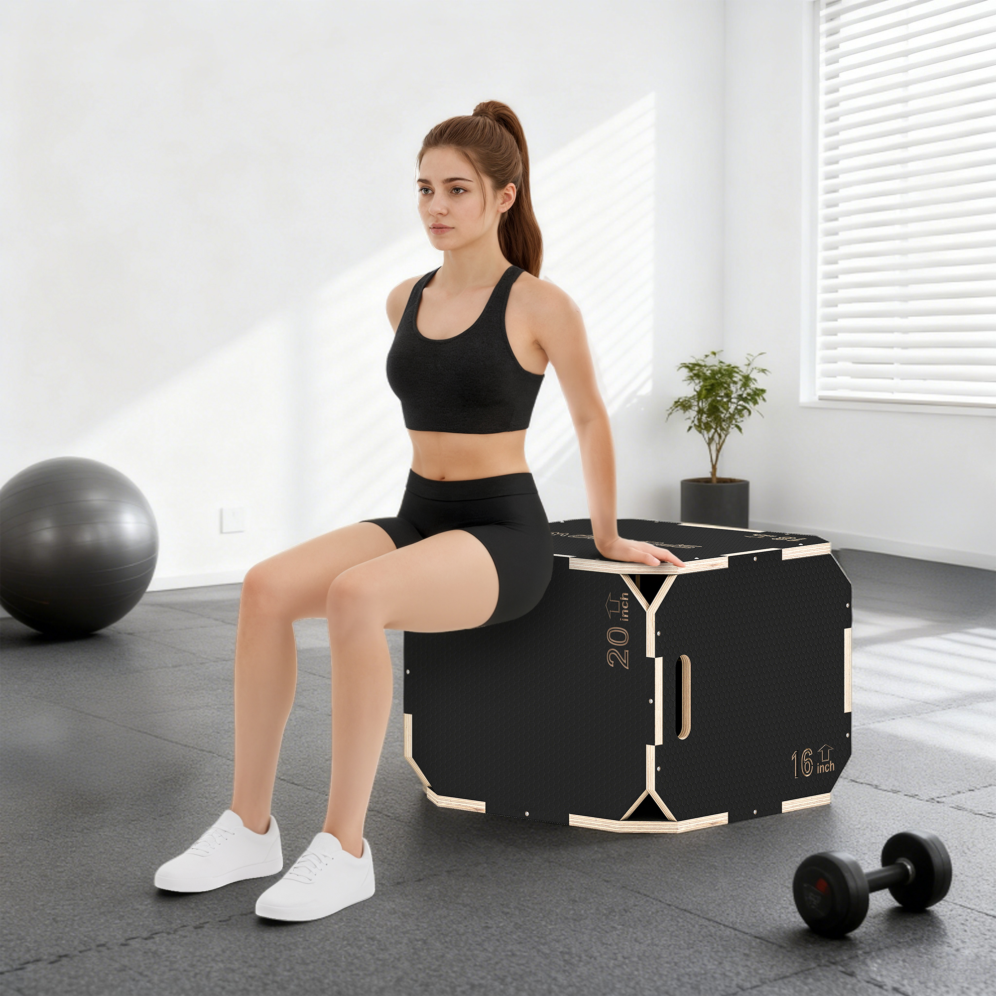 Una mujer se sienta en una caja negra en un gimnasio con pesas y balón.