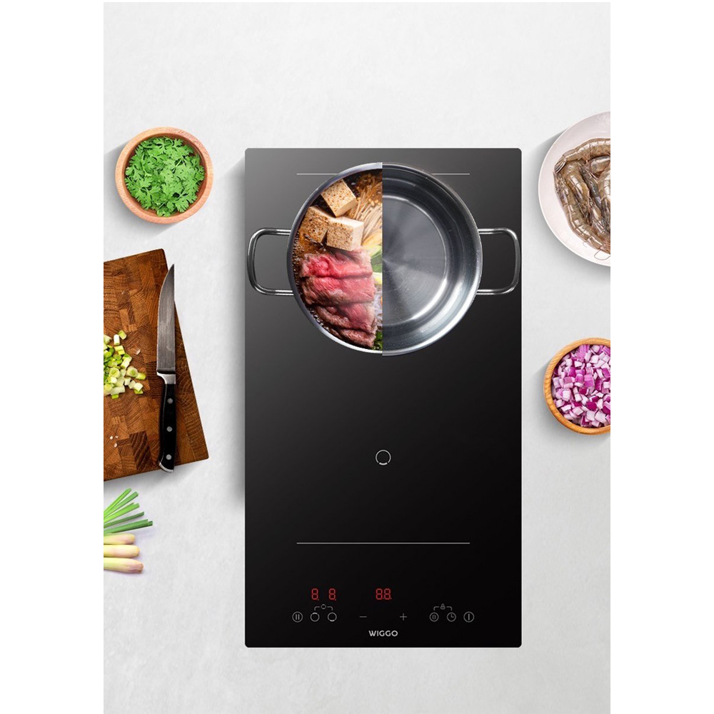 A pot with ingredients on an induction cooktop, next to chopped vegetables and shrimp.
