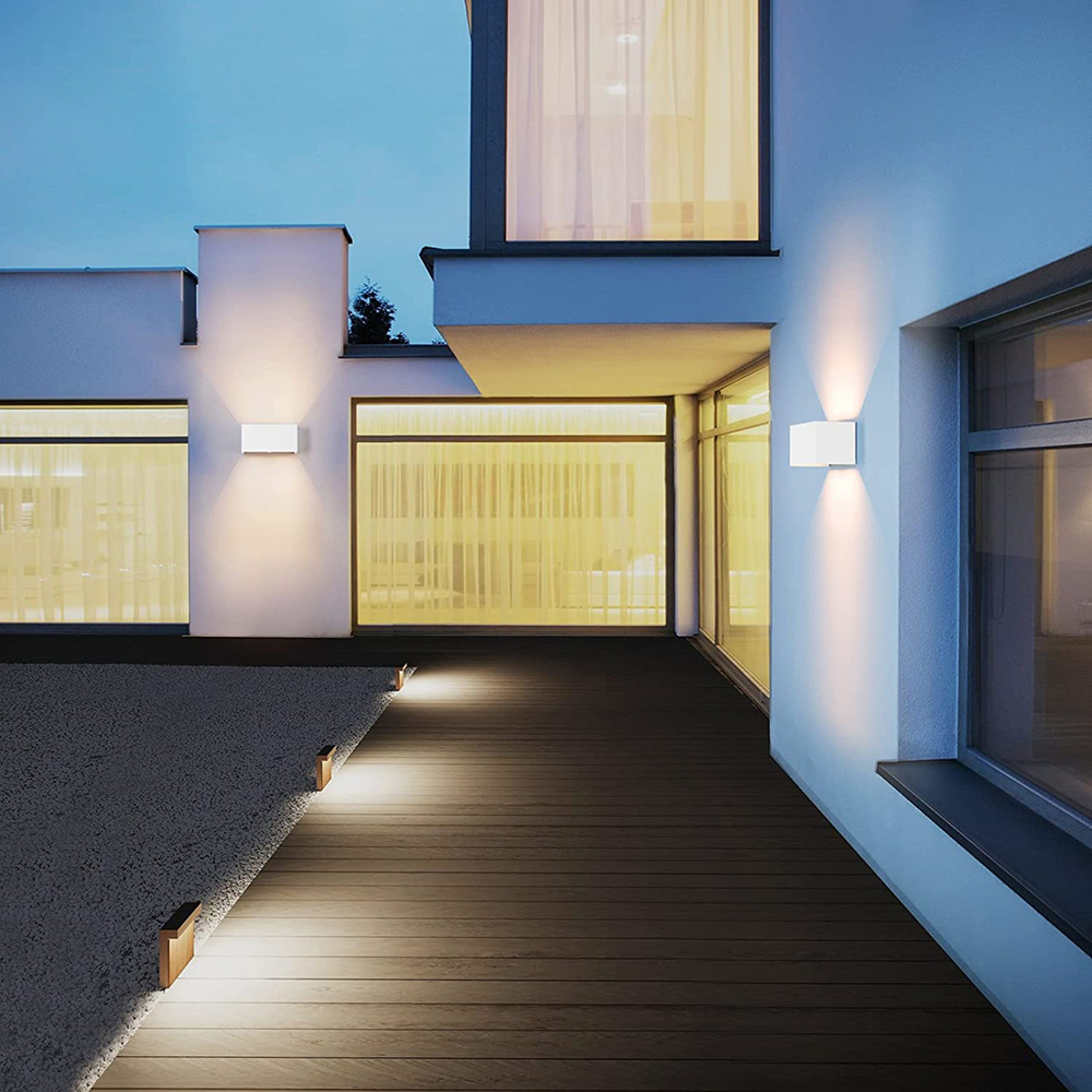 Moderne weiße Villa mit Außenbeleuchtung bei Dämmerung, Holzdeck, Kiesgarten.
