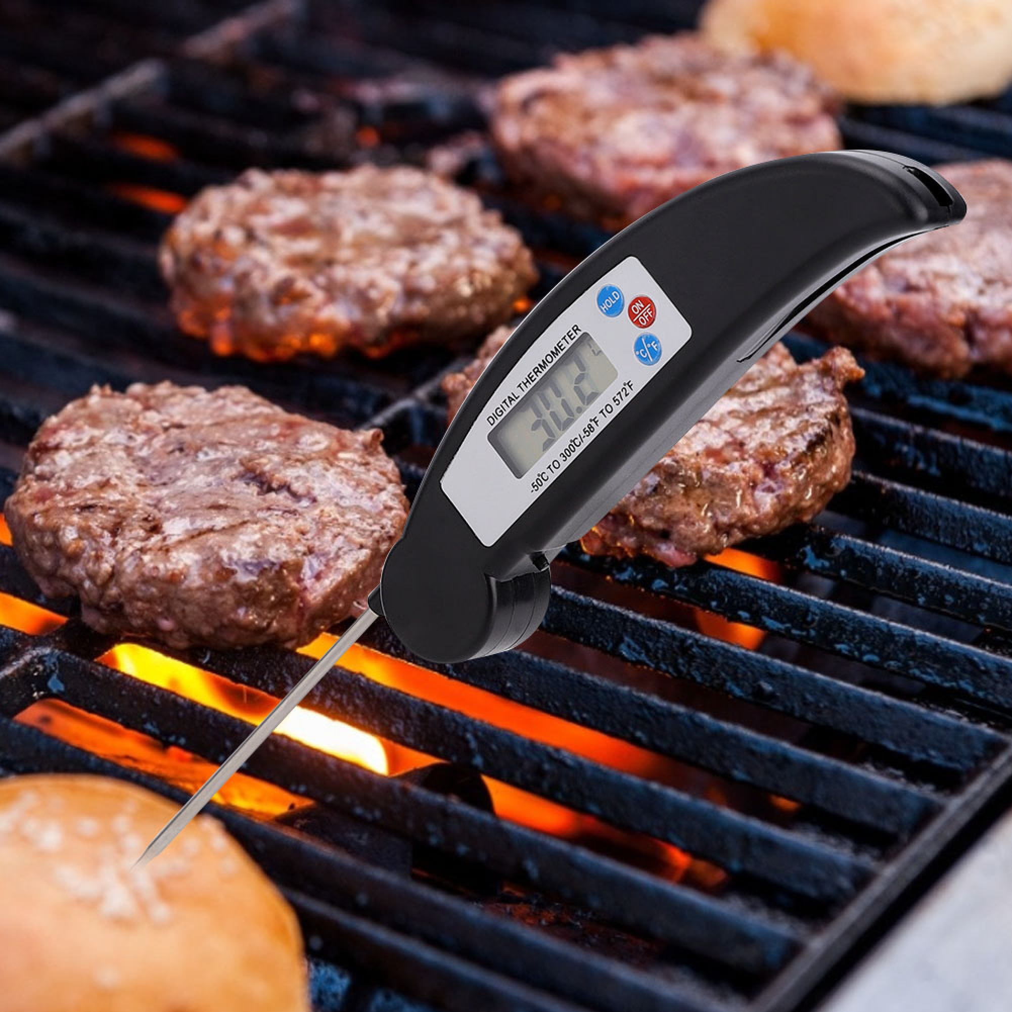 Digitalthermometer misst Hamburger auf einem Grill mit glühender Kohle.