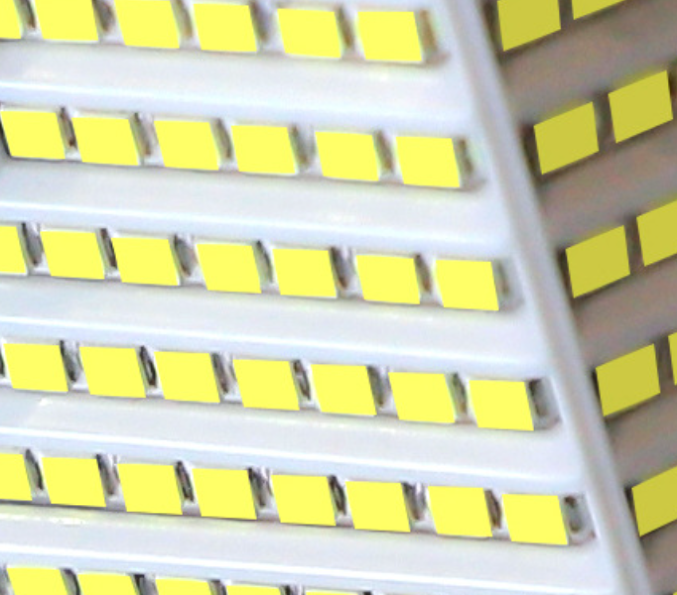 Naheaufnahme von Reihen gelber LEDs auf weißer Leiterplatte.