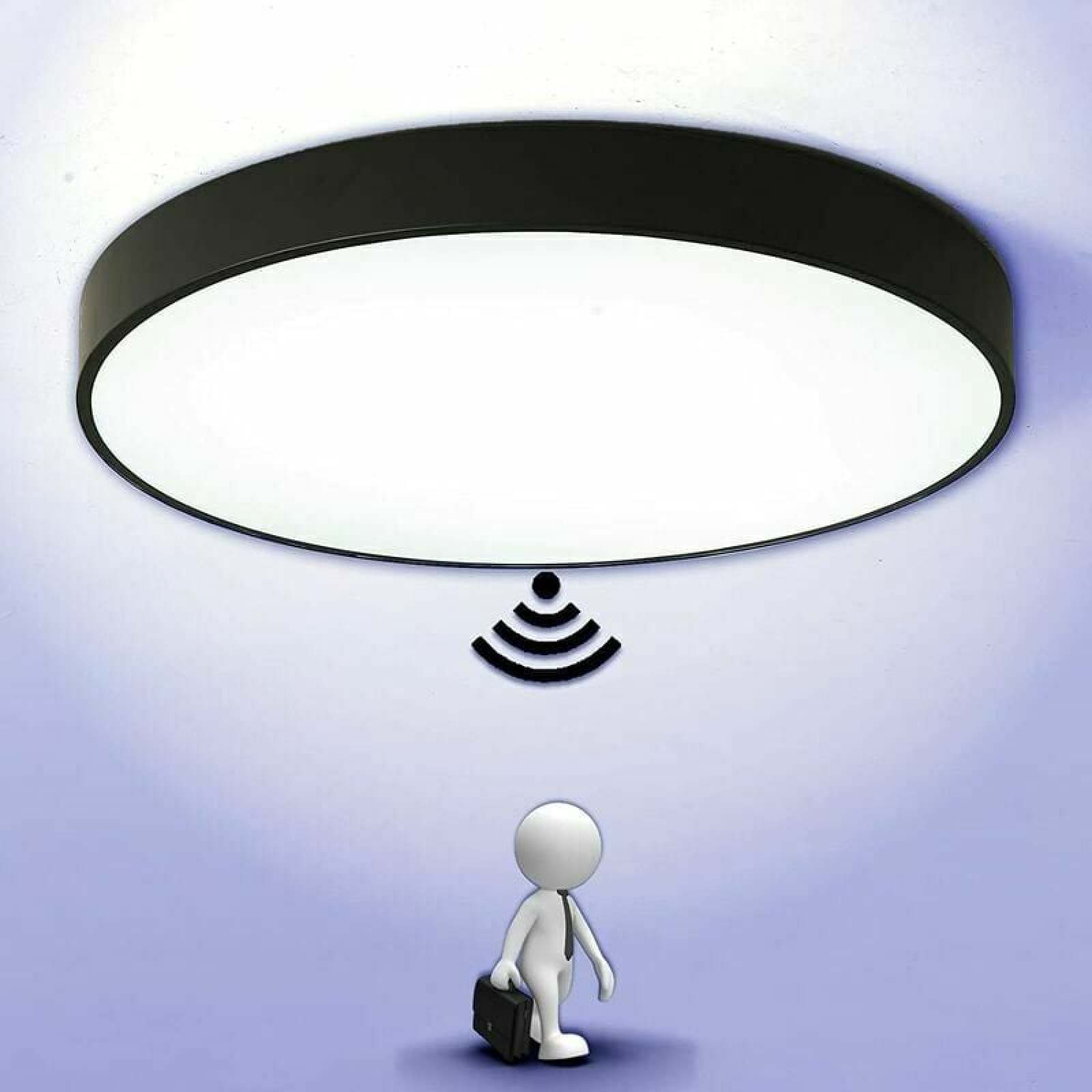 Eine runde LED-Deckenleuchte mit schwarzem Rand und einem WLAN-Symbol über einer kleinen Figur.