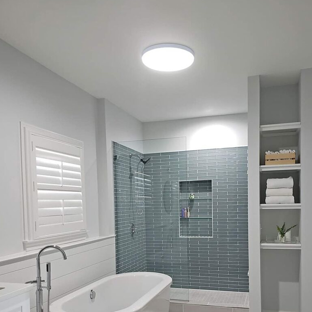 Modernes Badezimmer mit freistehender Wanne, Glasduschkabine mit grauen Fliesen, Fenster und Regal.