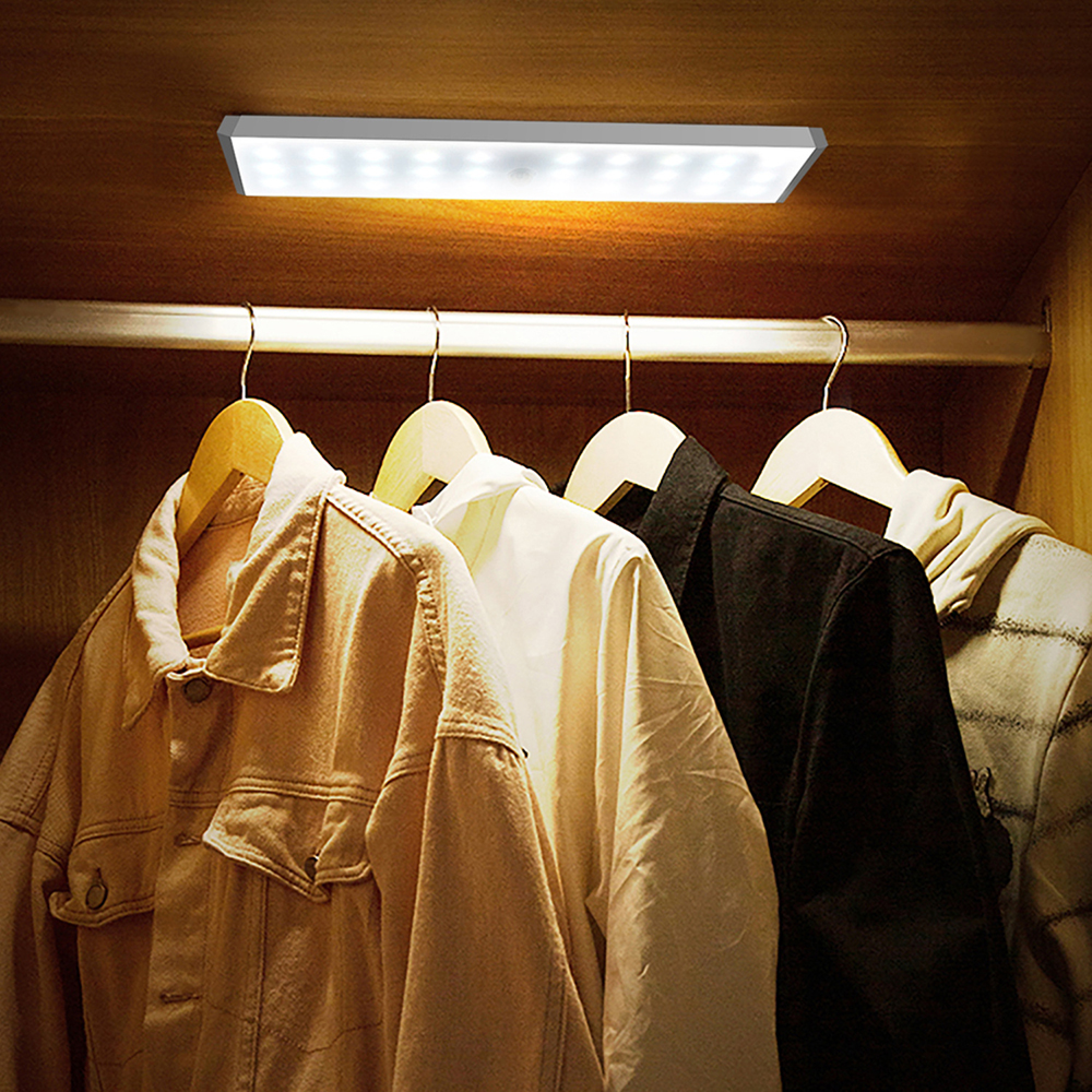 LED-Leiste beleuchtet Kleiderschrank mit hängenden Kleidungsstücken.