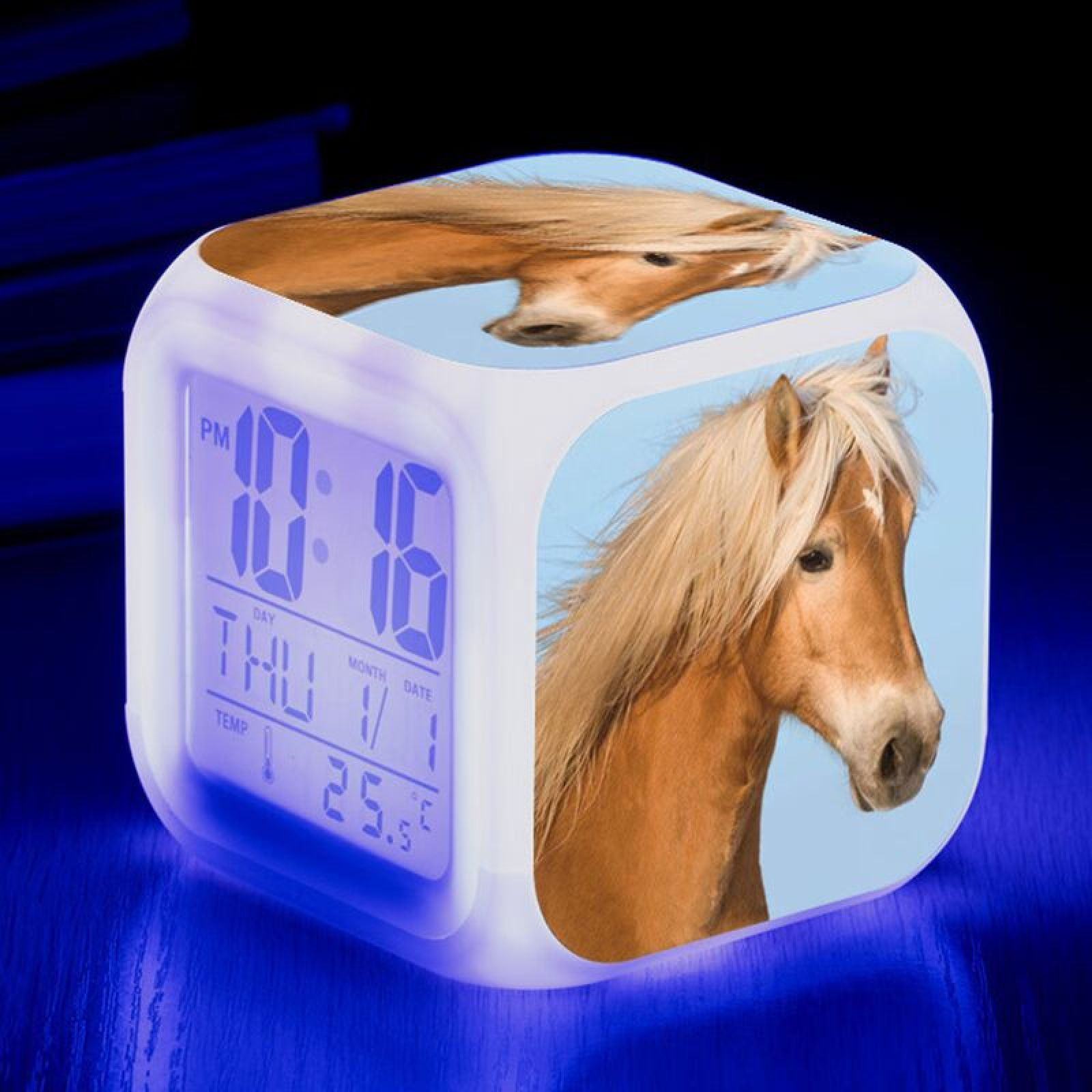 Ein leuchtender Würfel-Wecker mit Pferdebild und blauer Digitalanzeige.