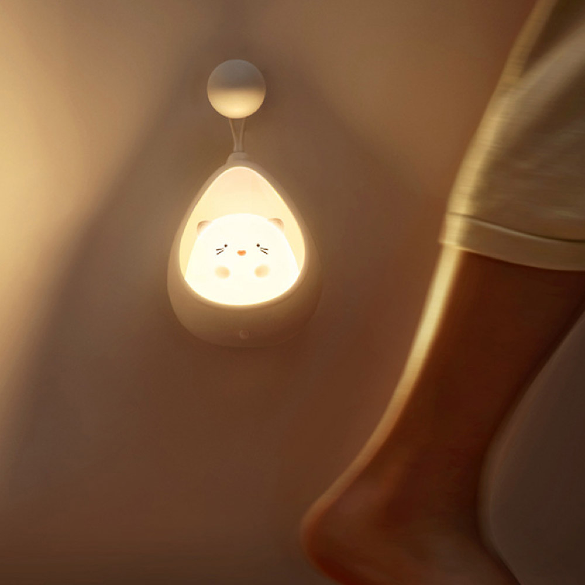 Eine niedliche Nachtlampe in Form eines Bärengesichts hängt an einer Wand.