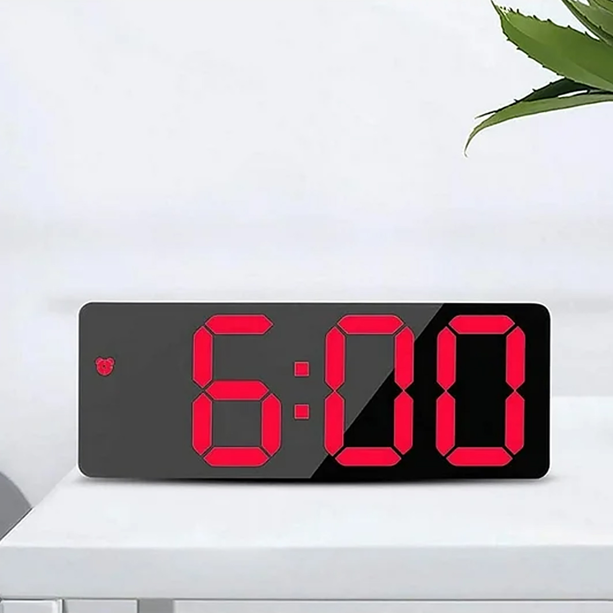 Digitaluhr zeigt 6:00 mit roten Ziffern auf schwarzem Display.