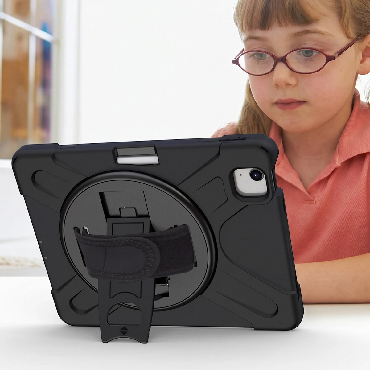 Ein junges Mädchen mit Brille schaut auf ein schwarzes Tablet mit Ständer.
