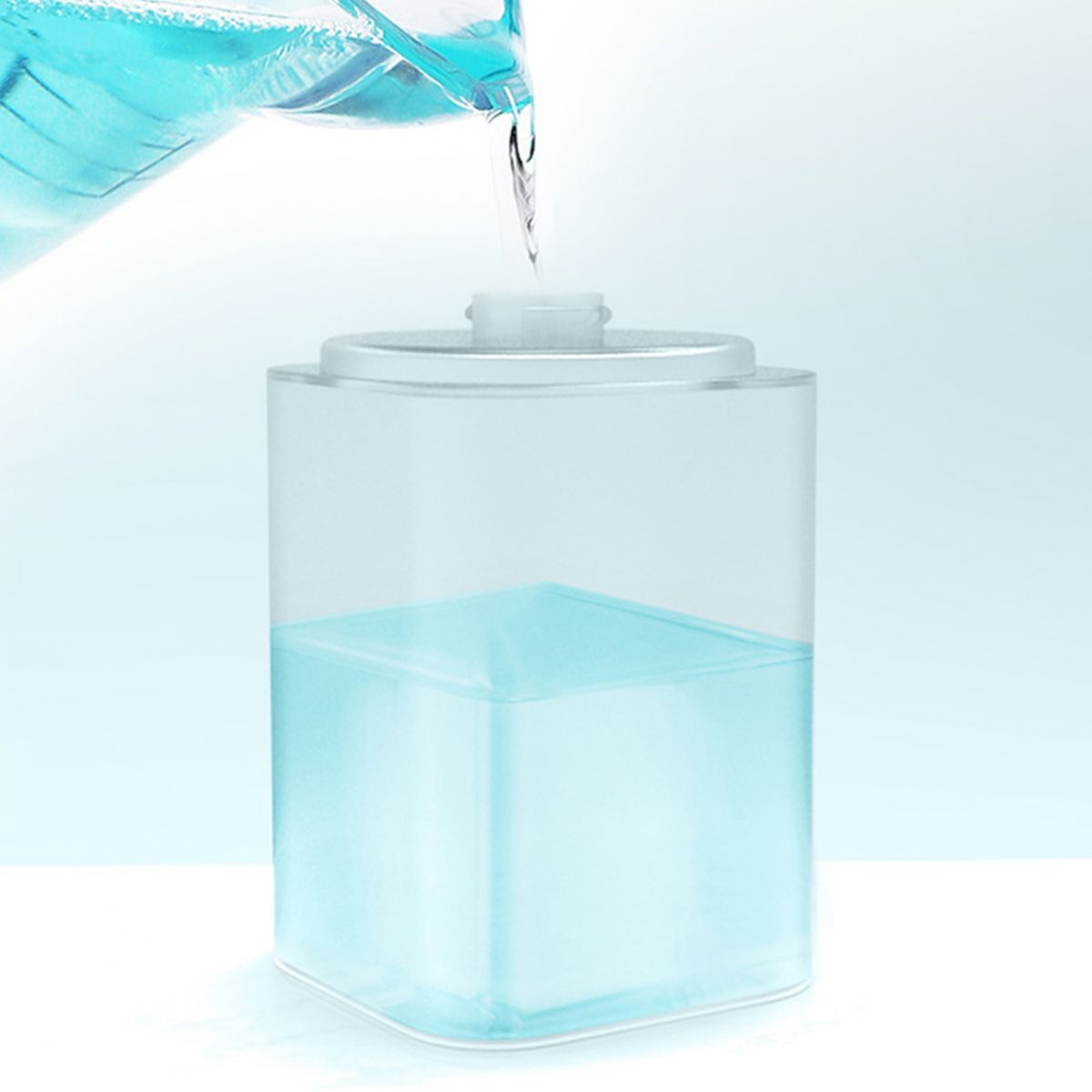 Blaues Wasser wird aus einem Krug in einen transparenten Behälter gegossen.
