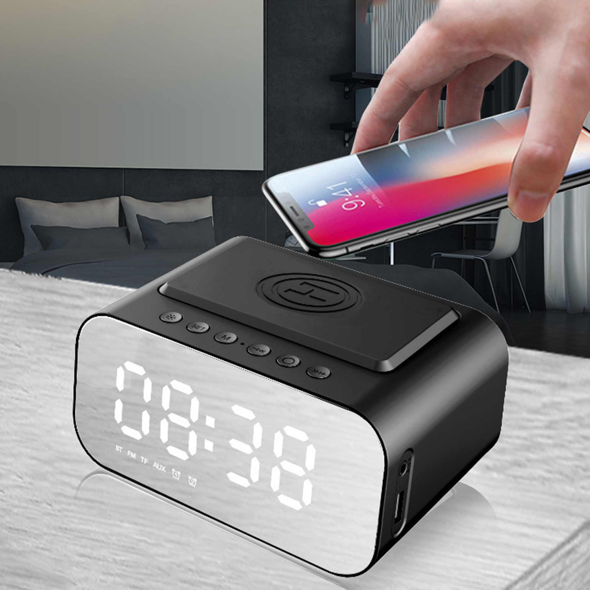 Ein schwarzer Wecker mit Ladefunktion wird von einer Hand mit einem Smartphone belegt.