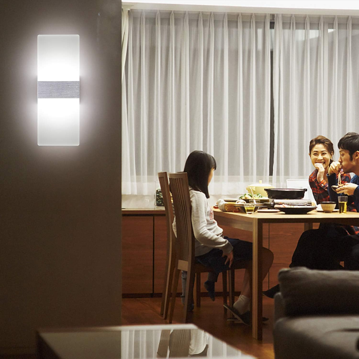 Familie isst am Tisch, beleuchtet von einer Wandlampe.