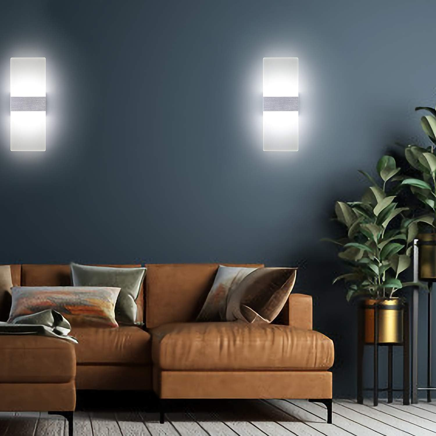 Ein braunes Ecksofa mit Kissen in einem Raum mit zwei Wandleuchten und einer Pflanze.