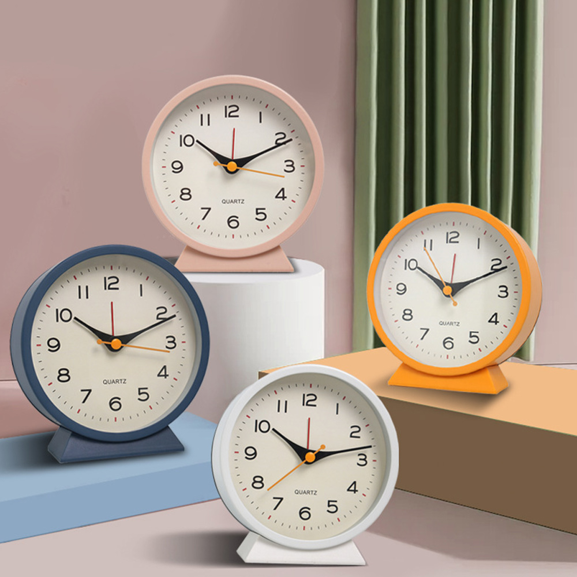 Vier Wecker in Rosa, Blau, Orange und Weiß stehen nebeneinander.