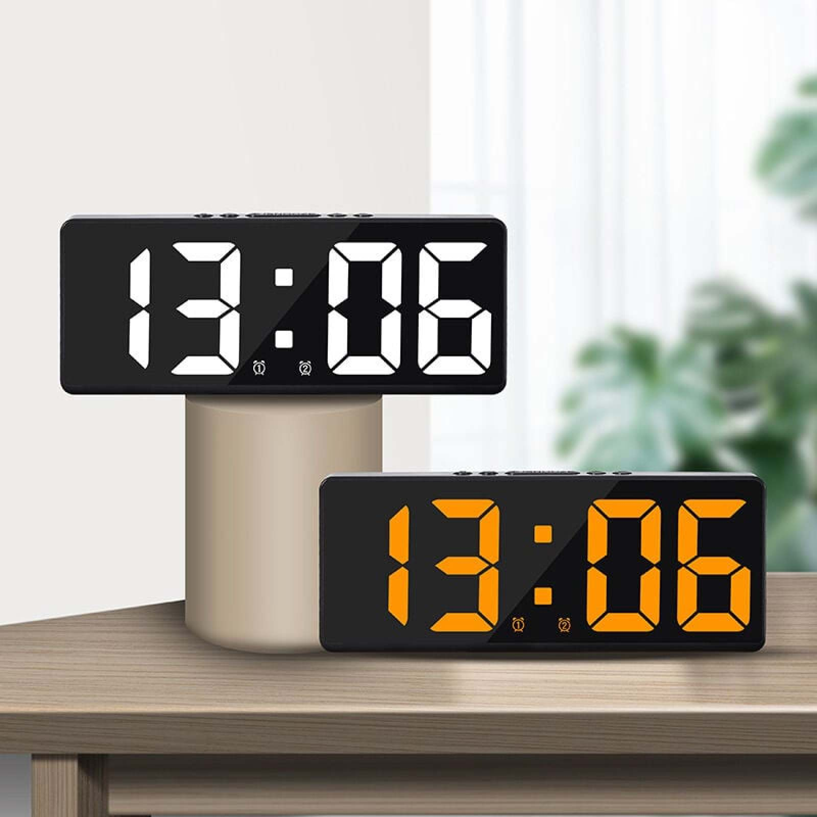 Zwei digitale Wecker auf einem Holztisch, einer weiß, der andere orange leuchtend.