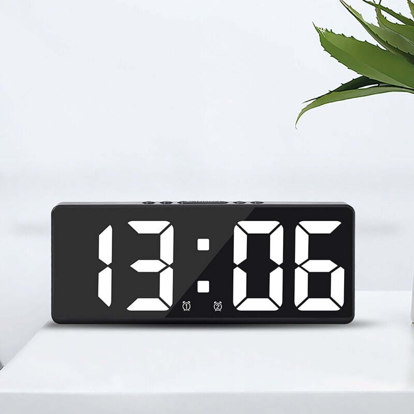 Ein schwarzer Digitaluhr zeigt 13:06 mit weißen Ziffern.