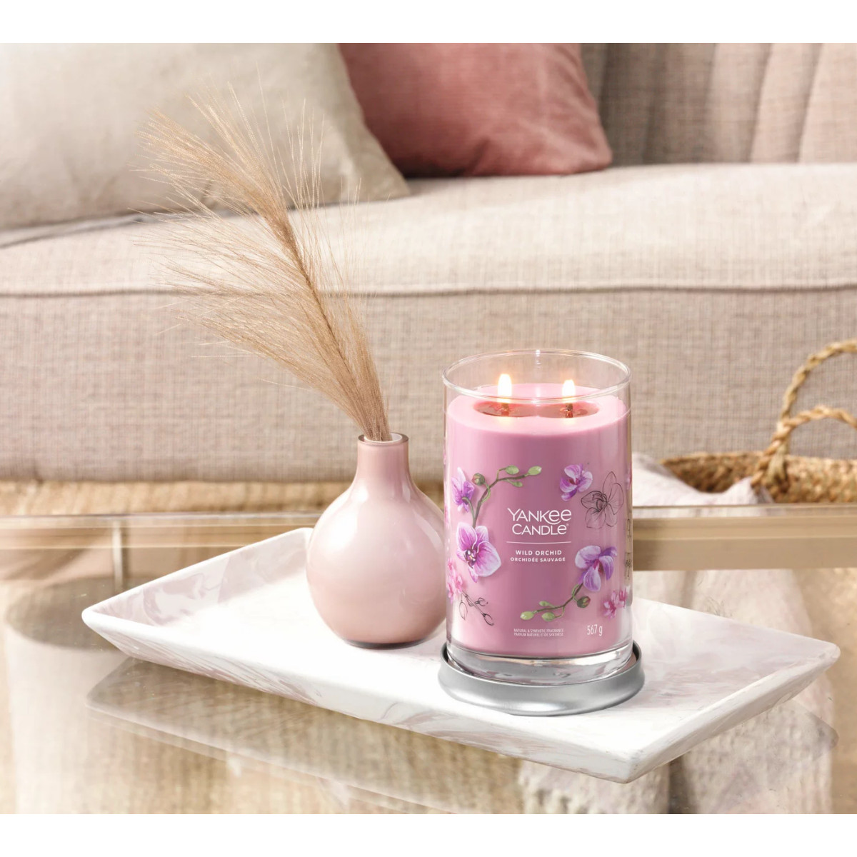 Ein rosa Yankee Candle mit Orchideenmotiv brennt auf einem Marmorsockel.
