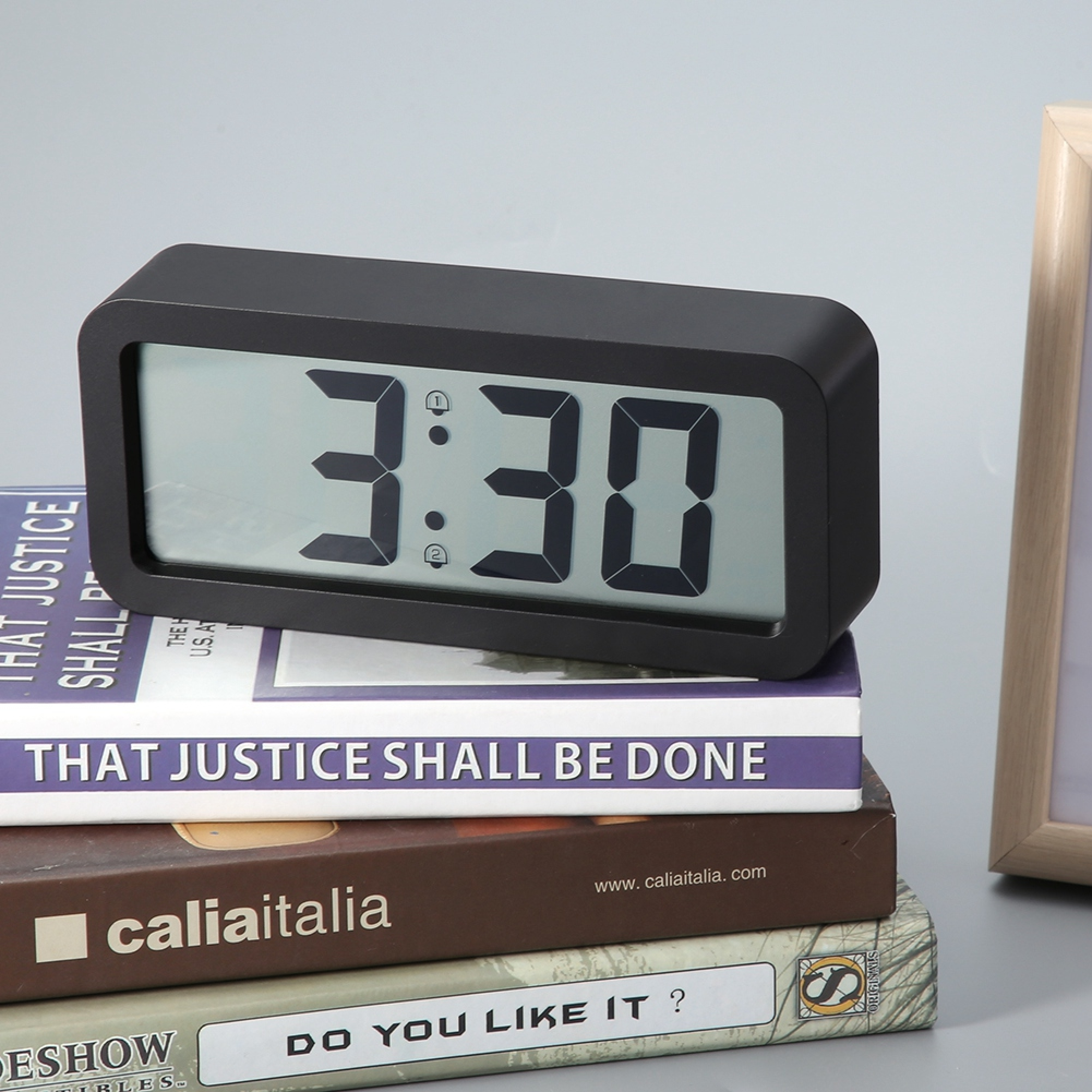 Ein schwarzer Digitalwecker zeigt 3:30 auf Büchern.